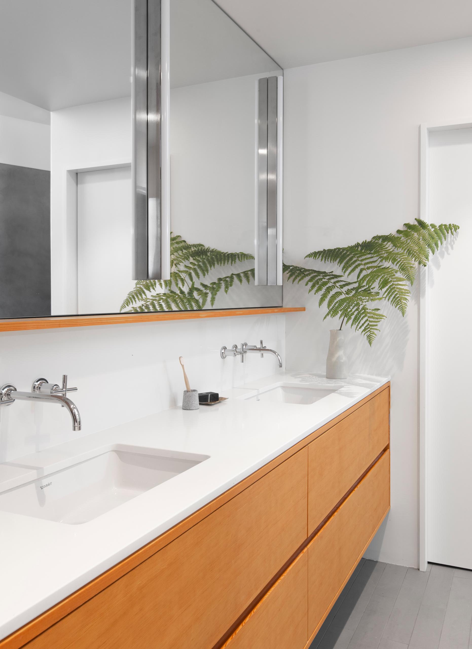 В этой современной главной ванной комнате столешница Caesarstone «Pure White» установлена ​​на туалетном столике из ели с утопленными ящиками.