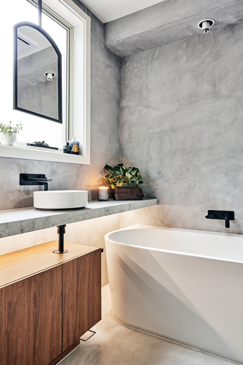 Идеи для ванных комнат - зеркало в матовой черной металлической рамке, подвешенное перед окном, позволило дизайнерам сохранить естественное освещение и вентиляцию, а белая ванна, слегка спрятанная под плавающей скамейкой для умывальника, помогла достичь максимальной желаемой роскоши замачивания. ванна. #BathroomIdeas # ModernBathroom