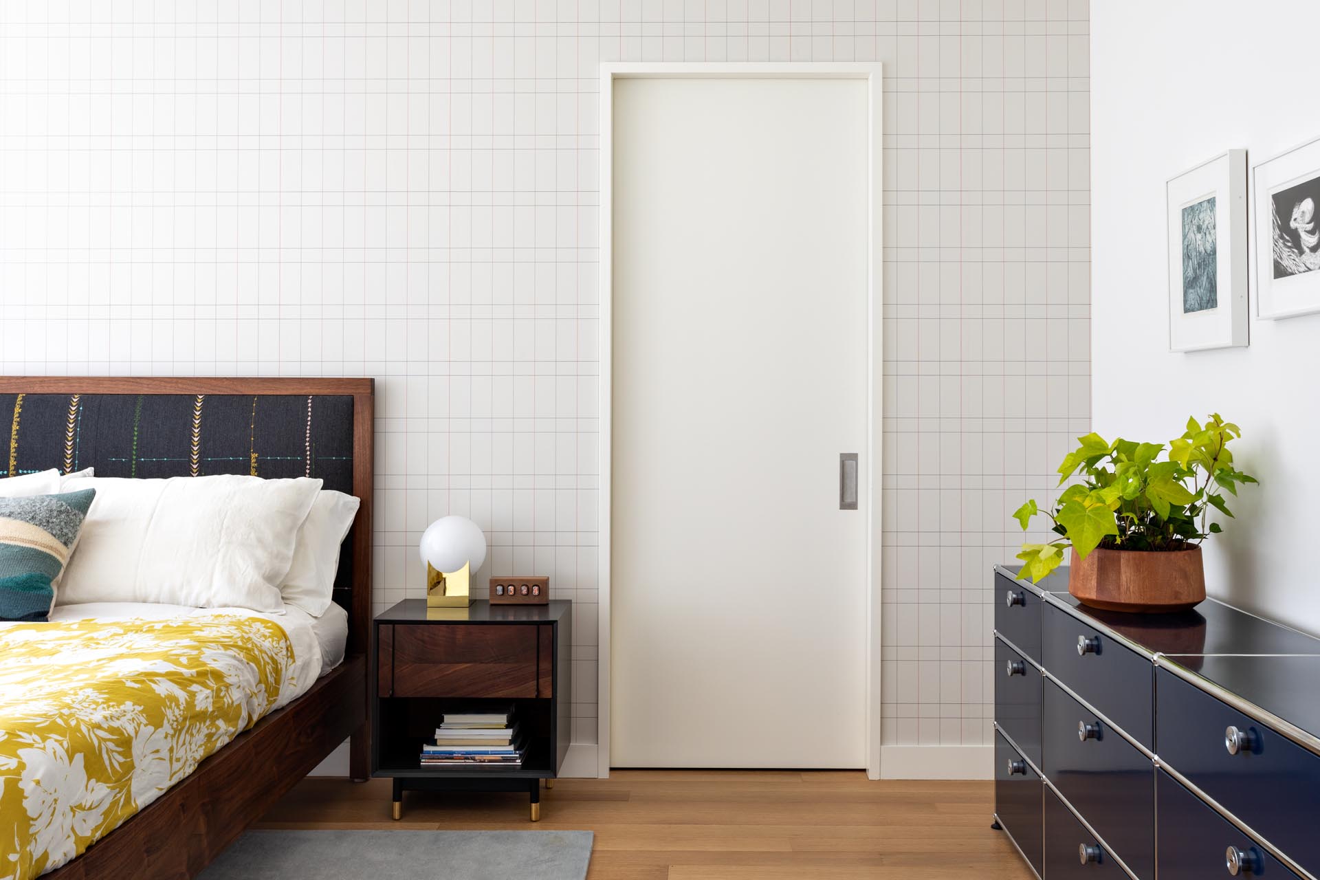 Современная главная спальня с деревянной мебелью, яркими элементами декора и стеной с графическим акцентом.
