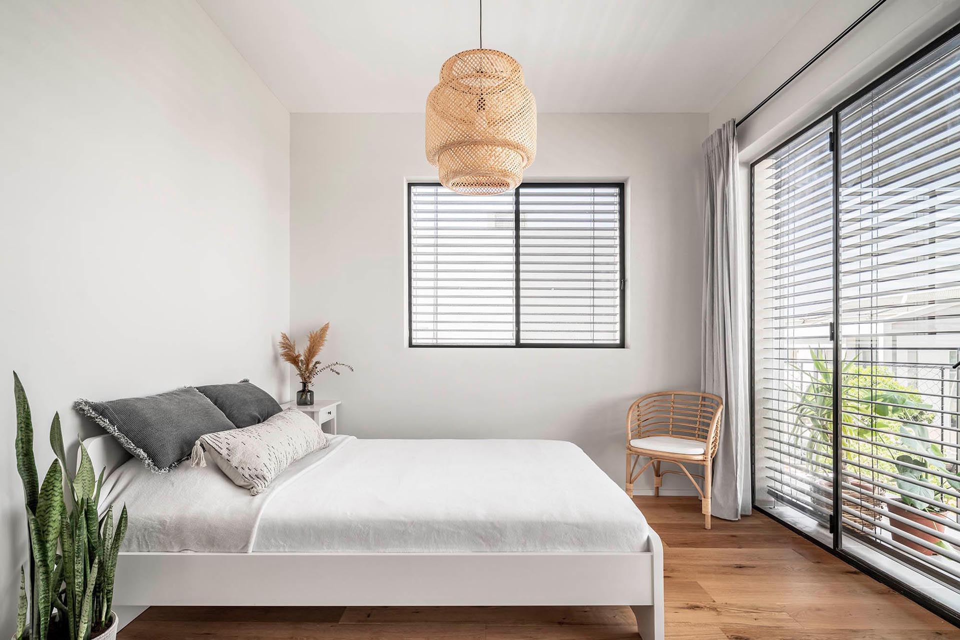 Эта современная спальня проста и ярка, со светлыми стенами, деревянными элементами декора и растениями.