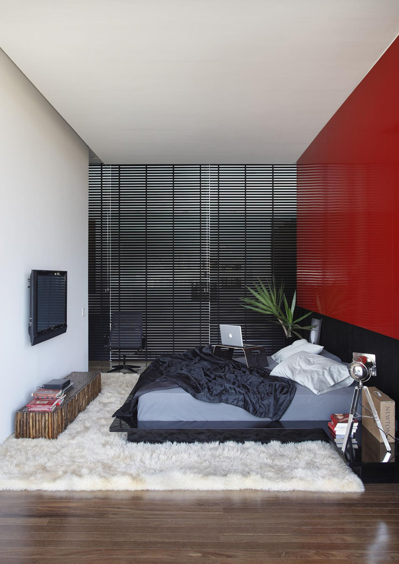 Ярко- красная декоративная стена выделяется в этой черно-белой спальне. 