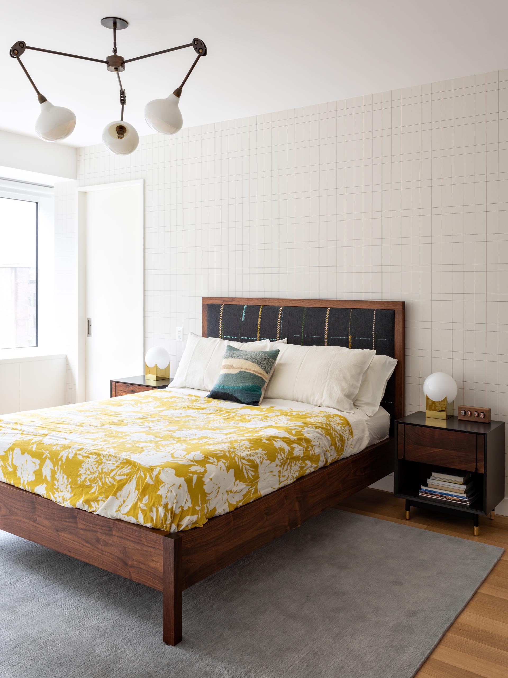 Современная главная спальня с деревянной мебелью, яркими элементами декора и стеной с графическим акцентом.