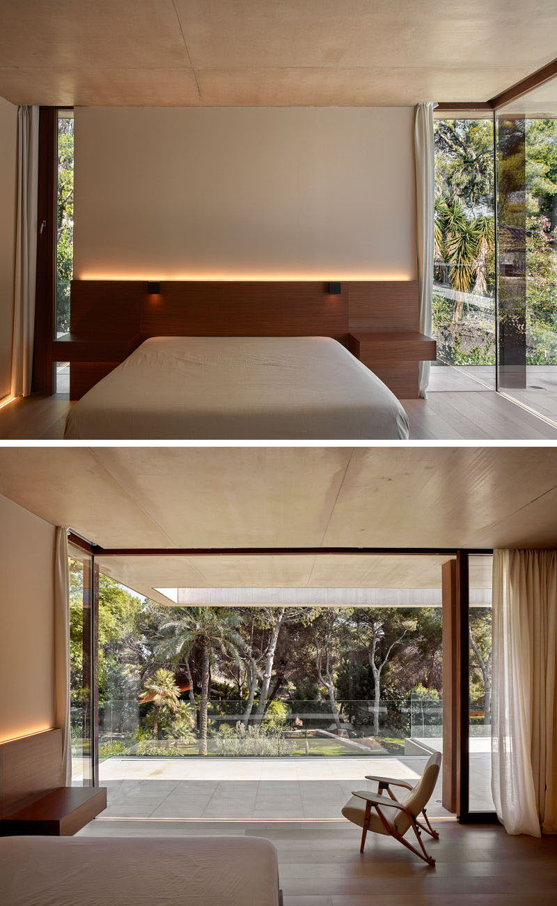 В этой современной спальне изголовье кровати имеет скрытое освещение, а окна и двери от пола до потолка выходят на задний двор.