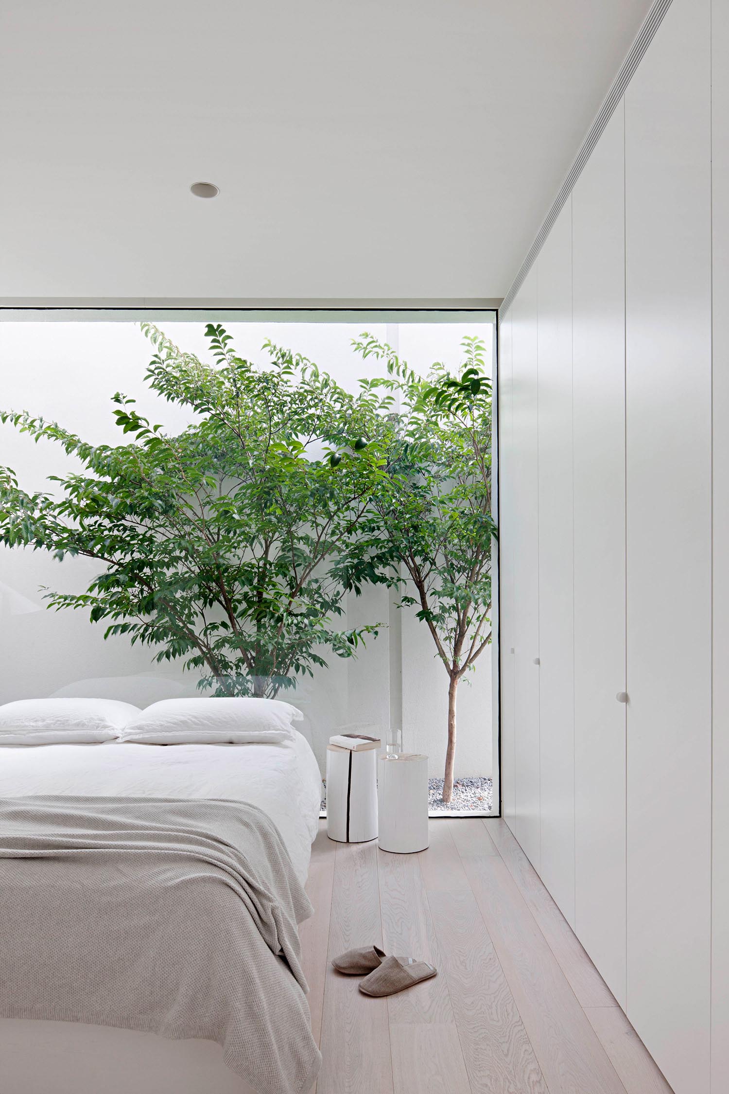 Современная спальня в нейтральной цветовой гамме с окном от пола до потолка.