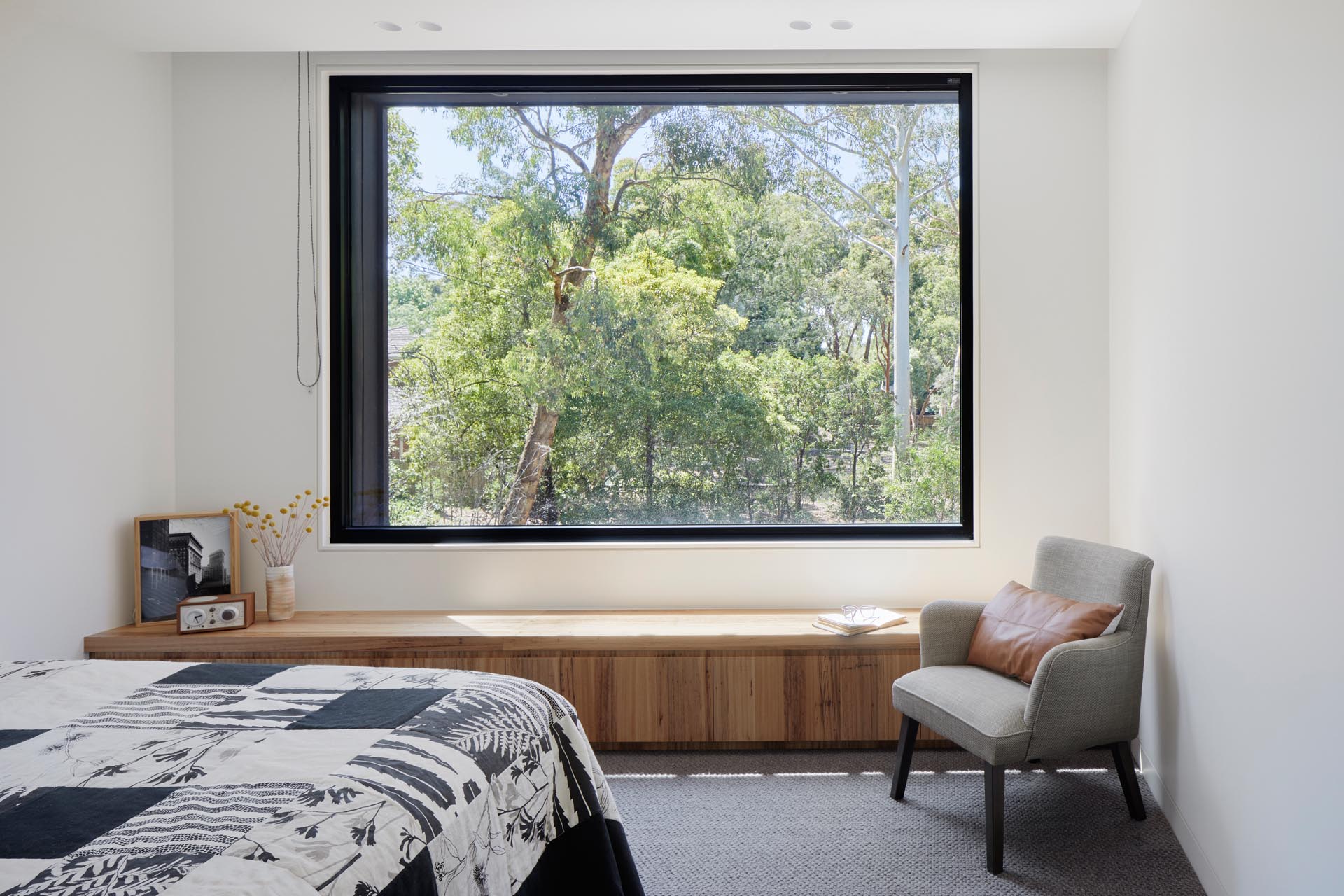 В этой современной спальне из большого окна открывается вид на деревья жевательной резинки снаружи, а плюшевый шерстяной ковер поглощает звук для уединения.