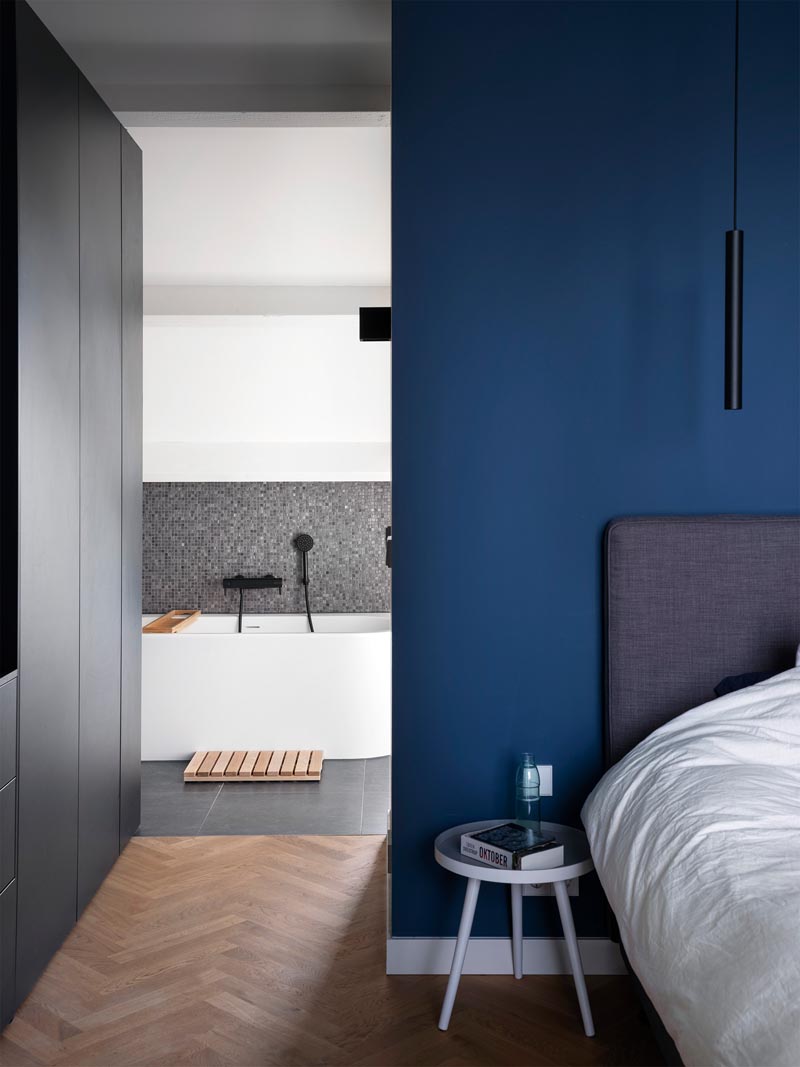 В этой современной главной спальне акцентная стена королевского синего цвета сочетается с черной мебелью, белой отделкой и деревянными полами в елочку. # МастерСпальня # Синие стены # Дизайн спальни