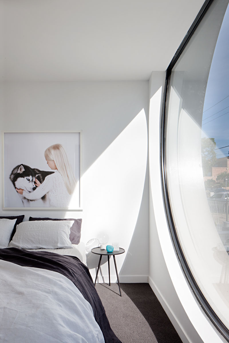 В этой спальне в стиле минимализма большое окно-иллюминатор обеспечивает много естественного света. # Дизайн спальни # Окно # Дизайн интерьера # Современная спальня