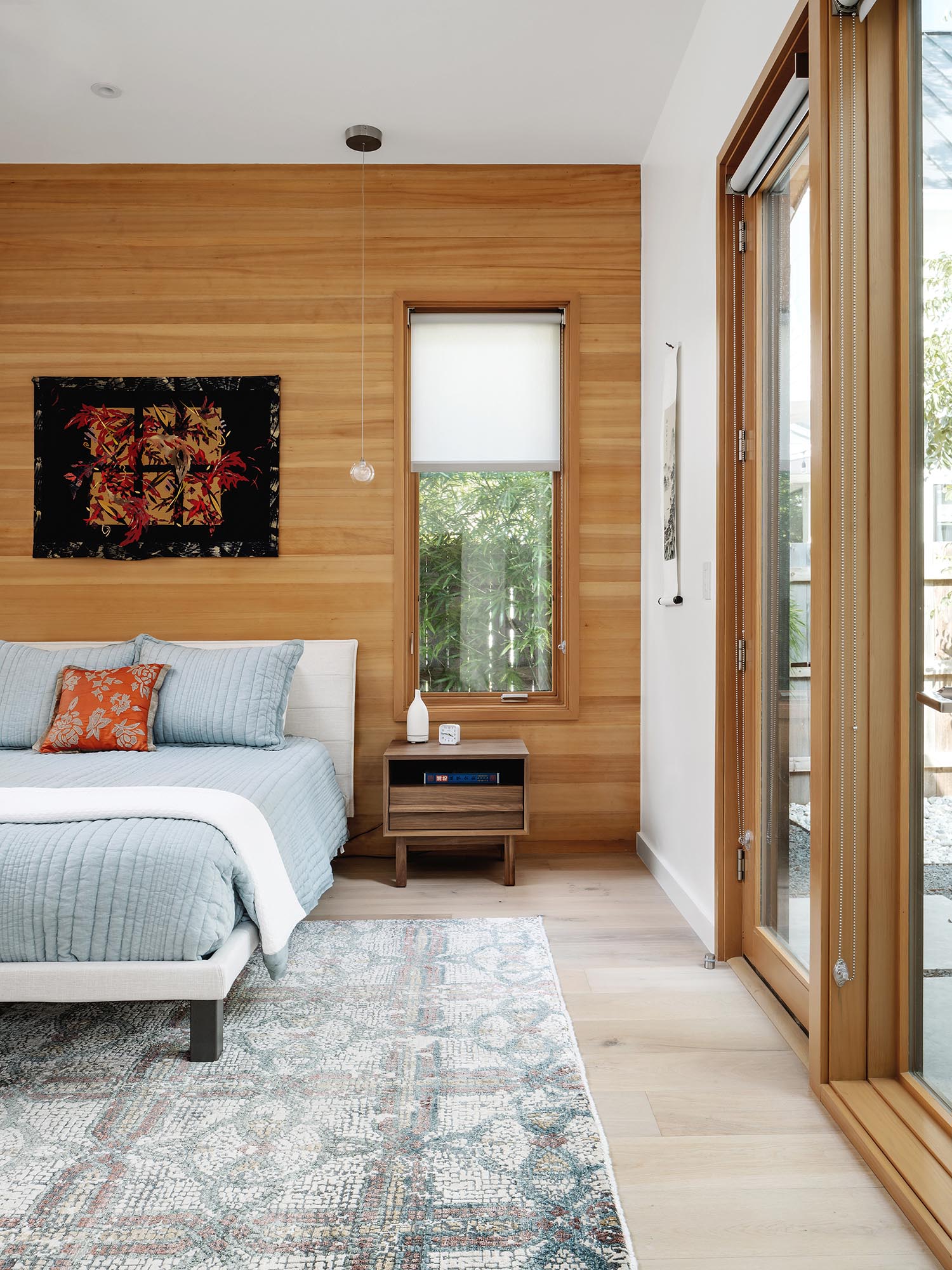 Современная спальня с голубым постельным бельем и стеной с деревянными акцентами.