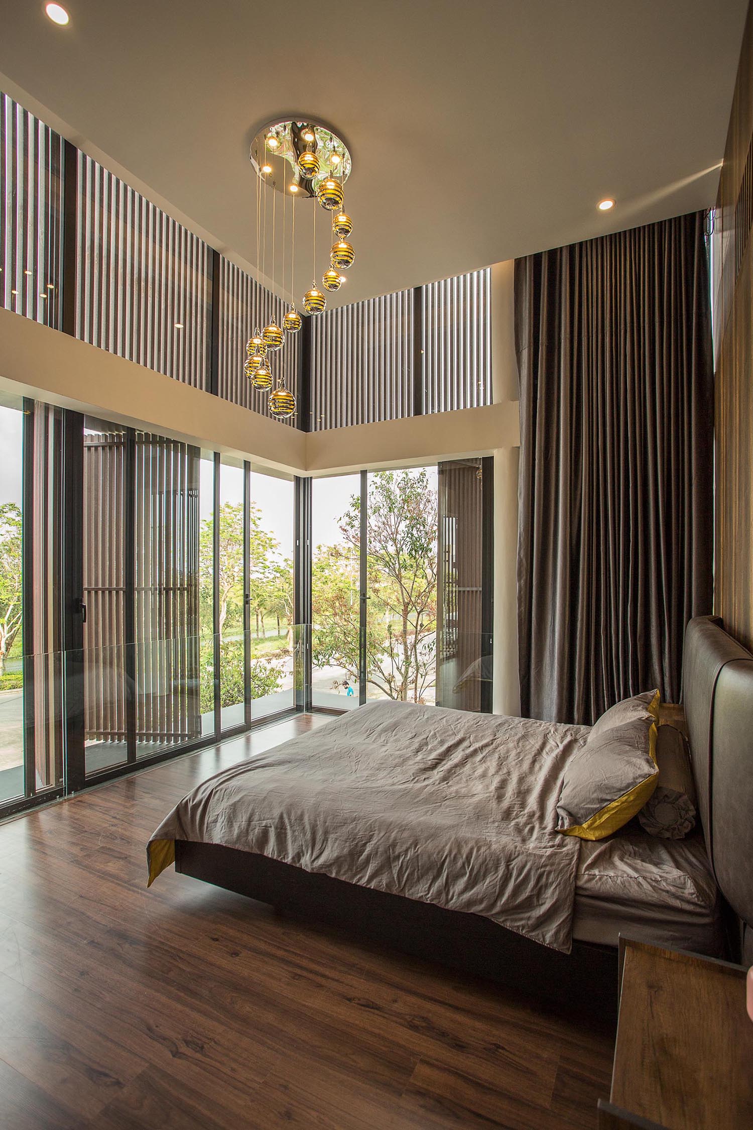 В современной спальне высокий потолок создает великолепный вид, в то время как стена с деревянным акцентом имеет полосы светодиодных светильников, которые проходят от потолка до пола.