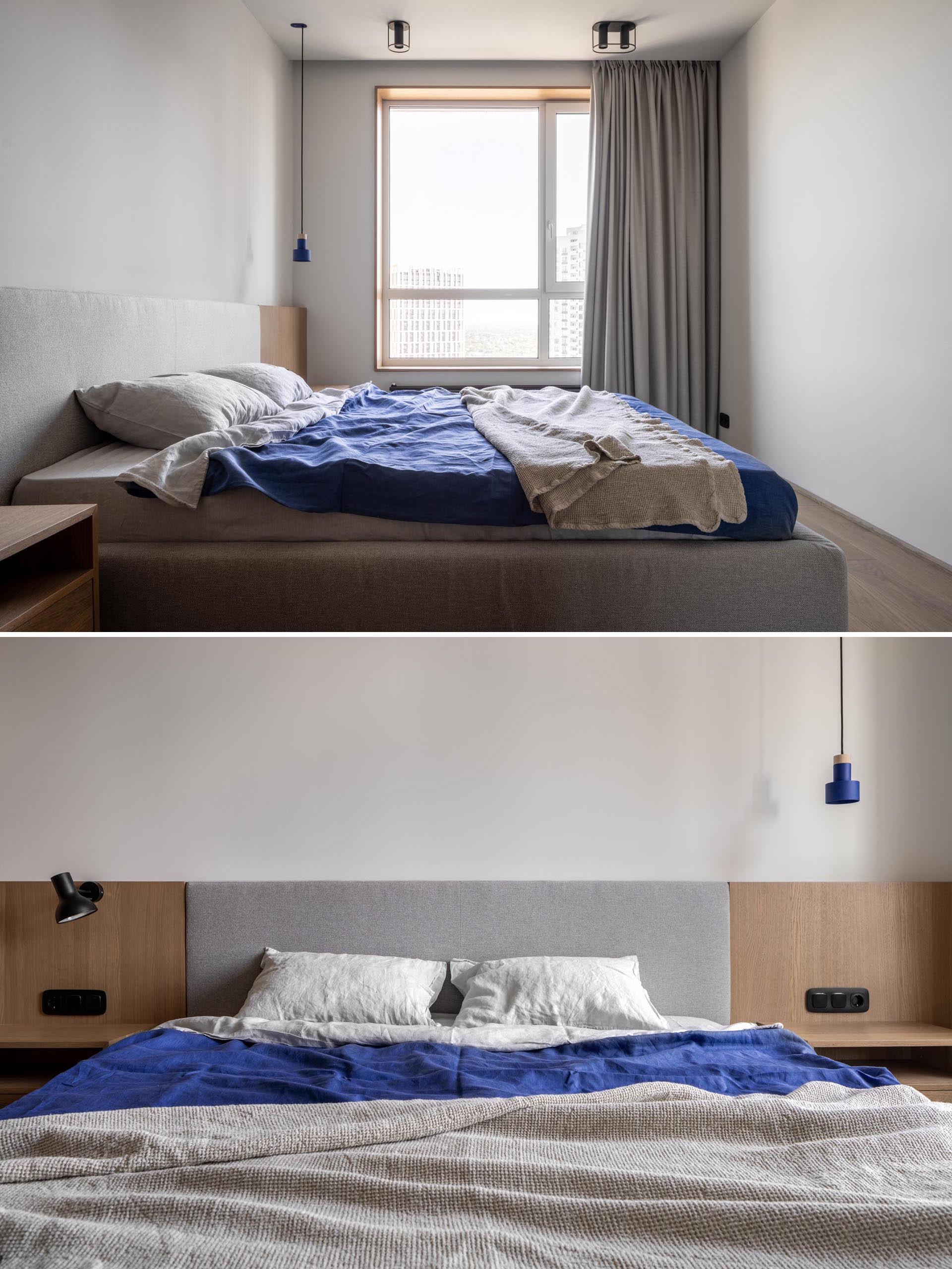 Современная спальня с серым обитым каркасом кровати и деревянными прикроватными тумбочками по бокам, а окна занавешены шторами от пола до потолка.