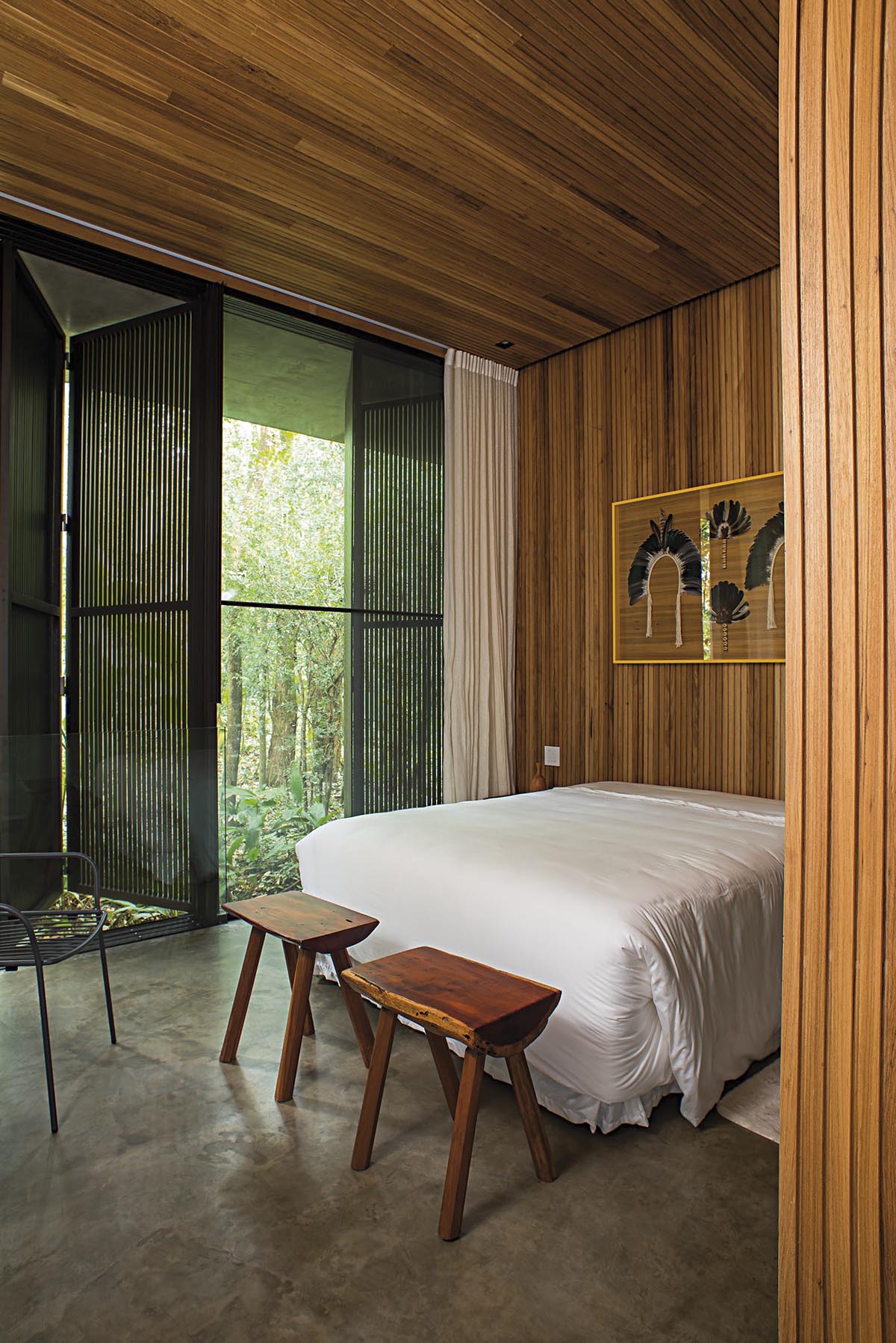 В этой современной спальне деревянный потолок продолжается до стены, создавая фон для кровати и произведений искусства. Деревянные ставни создают уединение, однако, когда они открыты, они позволяют естественному свету заливать комнату.