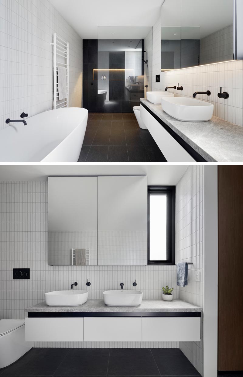 В душе этой современной ванной комнаты черная плитка на стенах украшена душевой нишей со скрытой подсветкой. Стеклянная перегородка для душа позволяет свету проходить по комнате. Черной плитке контрастируют белые плитки на стенах и другие белые акценты, такие как ванна, вешалка для полотенец, туалетный столик и раковины. #ModernBathroom #BlackAndWhiteBathroom #BathroomDesign #BlackTiles #ShowerNiche