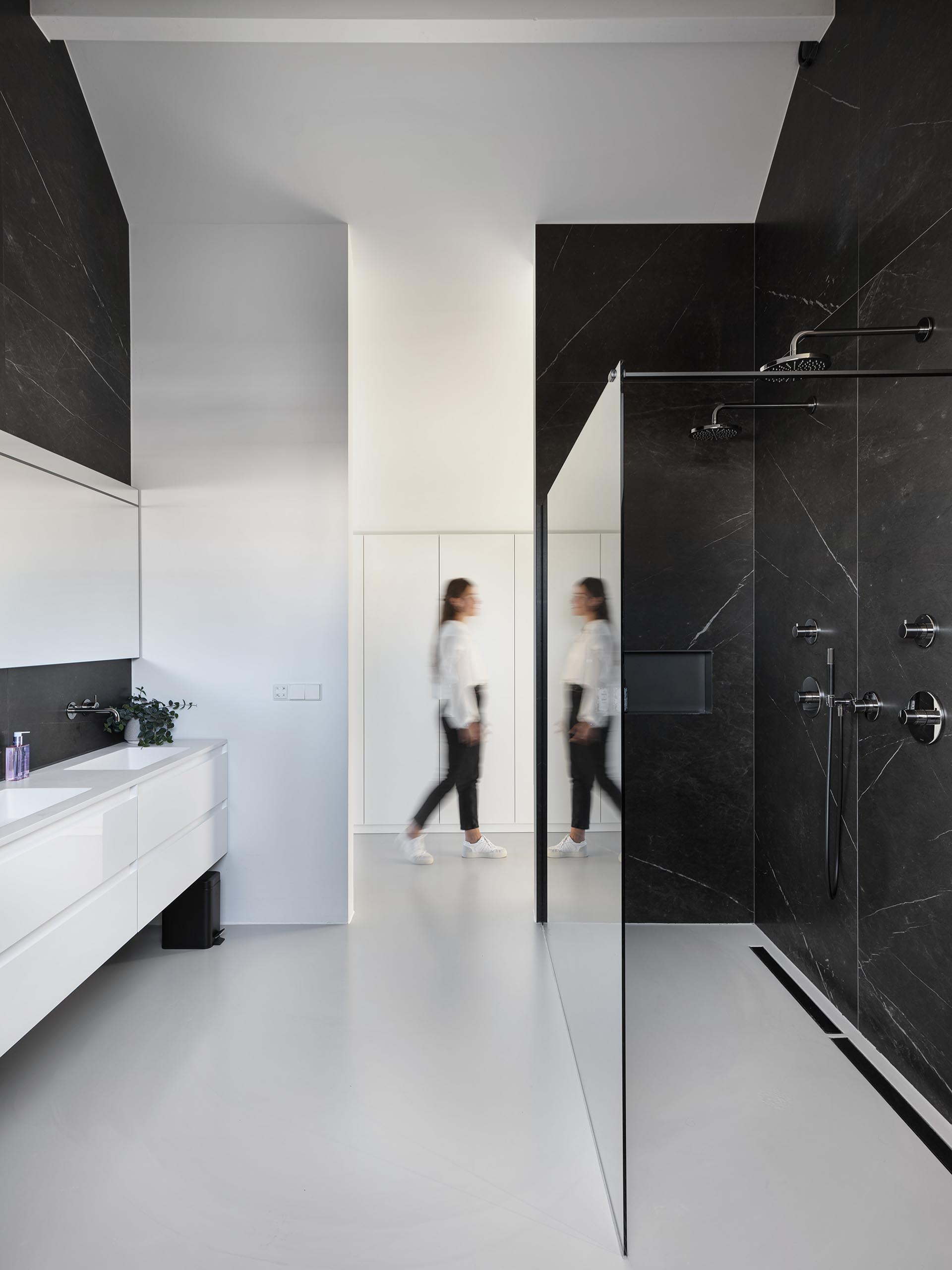 Стены этой современной ванной комнаты украшены черным камнем, который контрастирует с белым туалетным столиком.