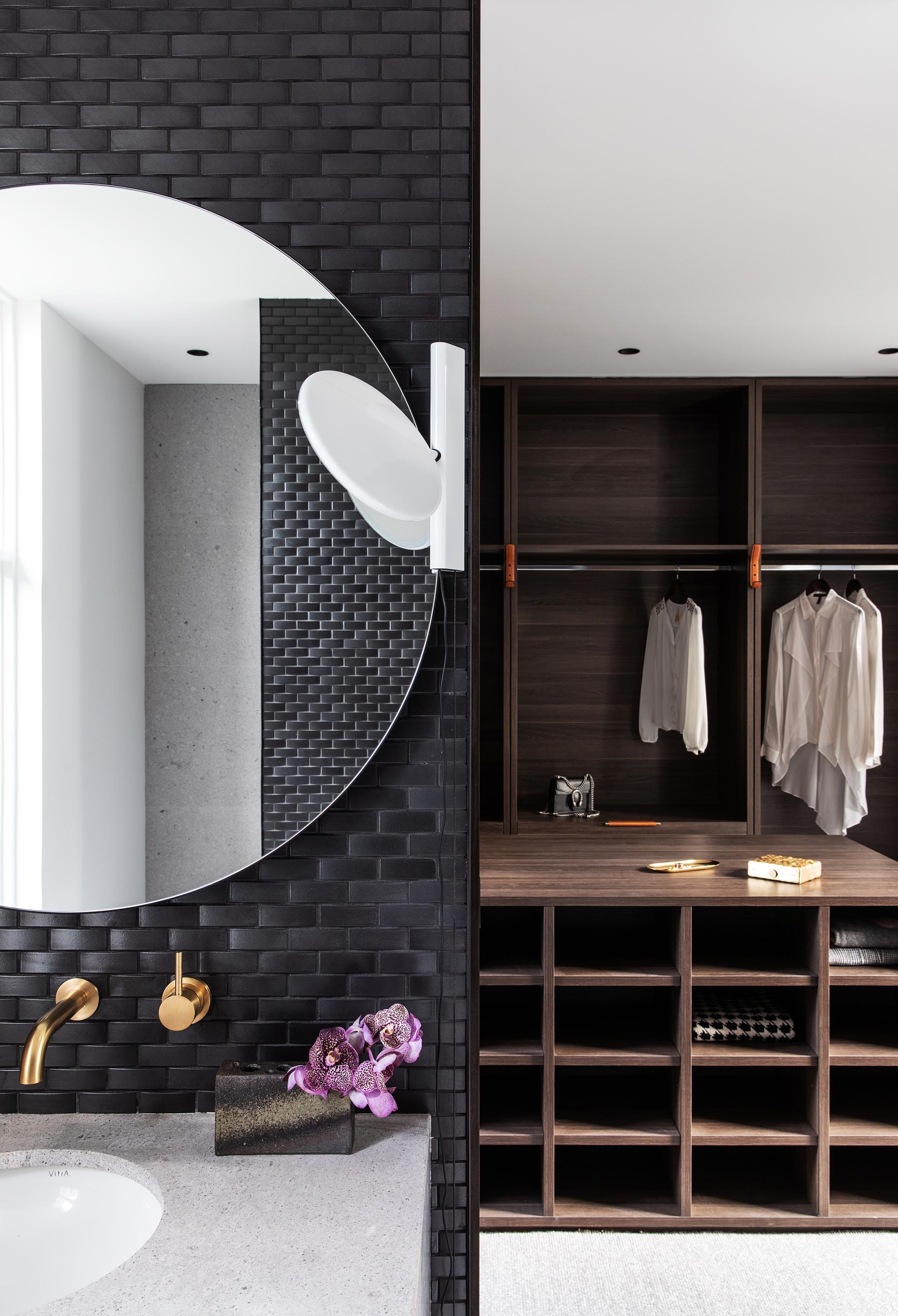 В главной ванной комнате стены покрыты черной плиткой, а круглые зеркала висят над белыми туалетными столиками с раковинами под ними. Также есть гардеробная с мебелью из темного дерева.
