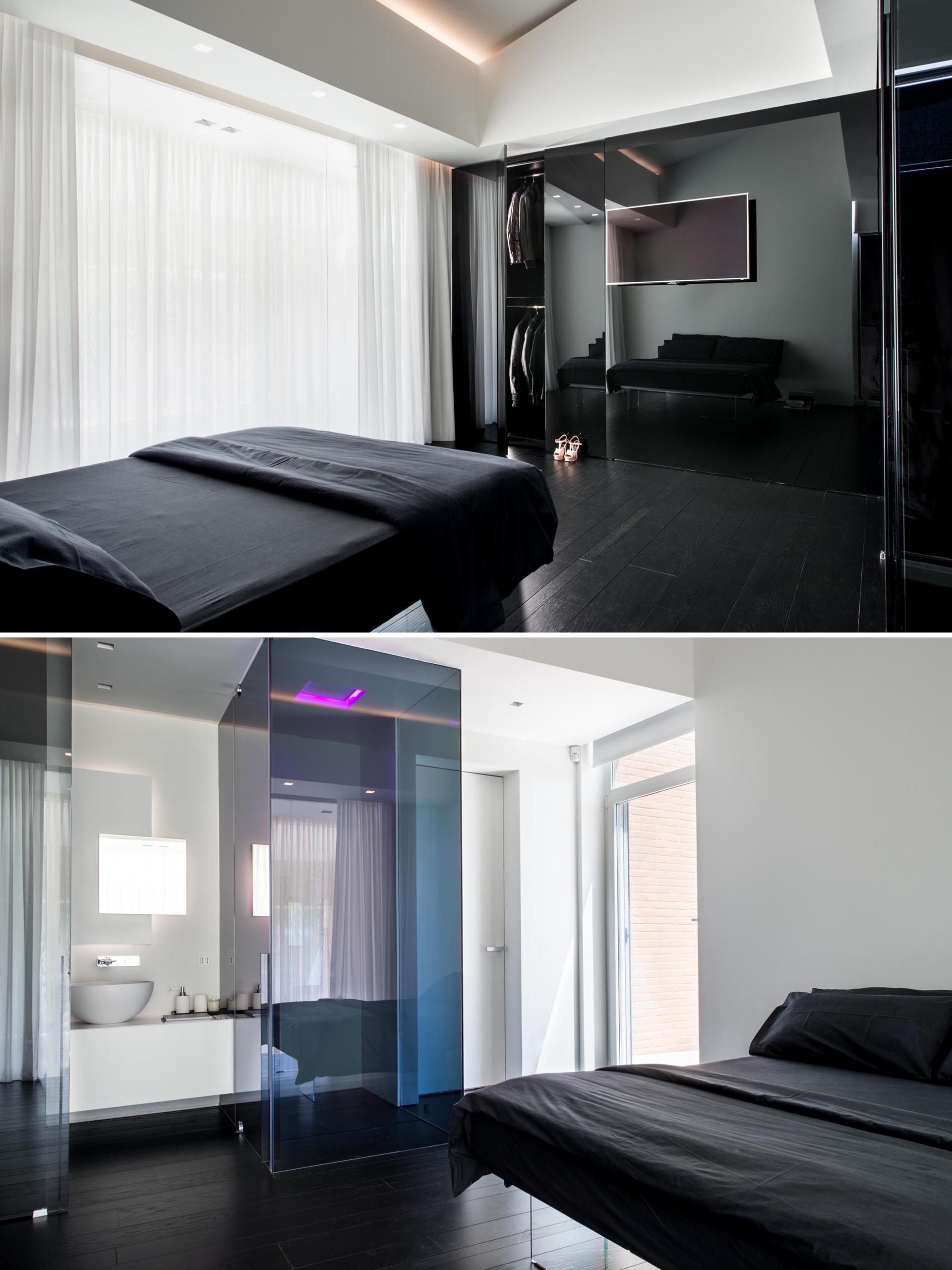 Современная спальня с черной кроватью, белыми стенами и собственной ванной комнатой.