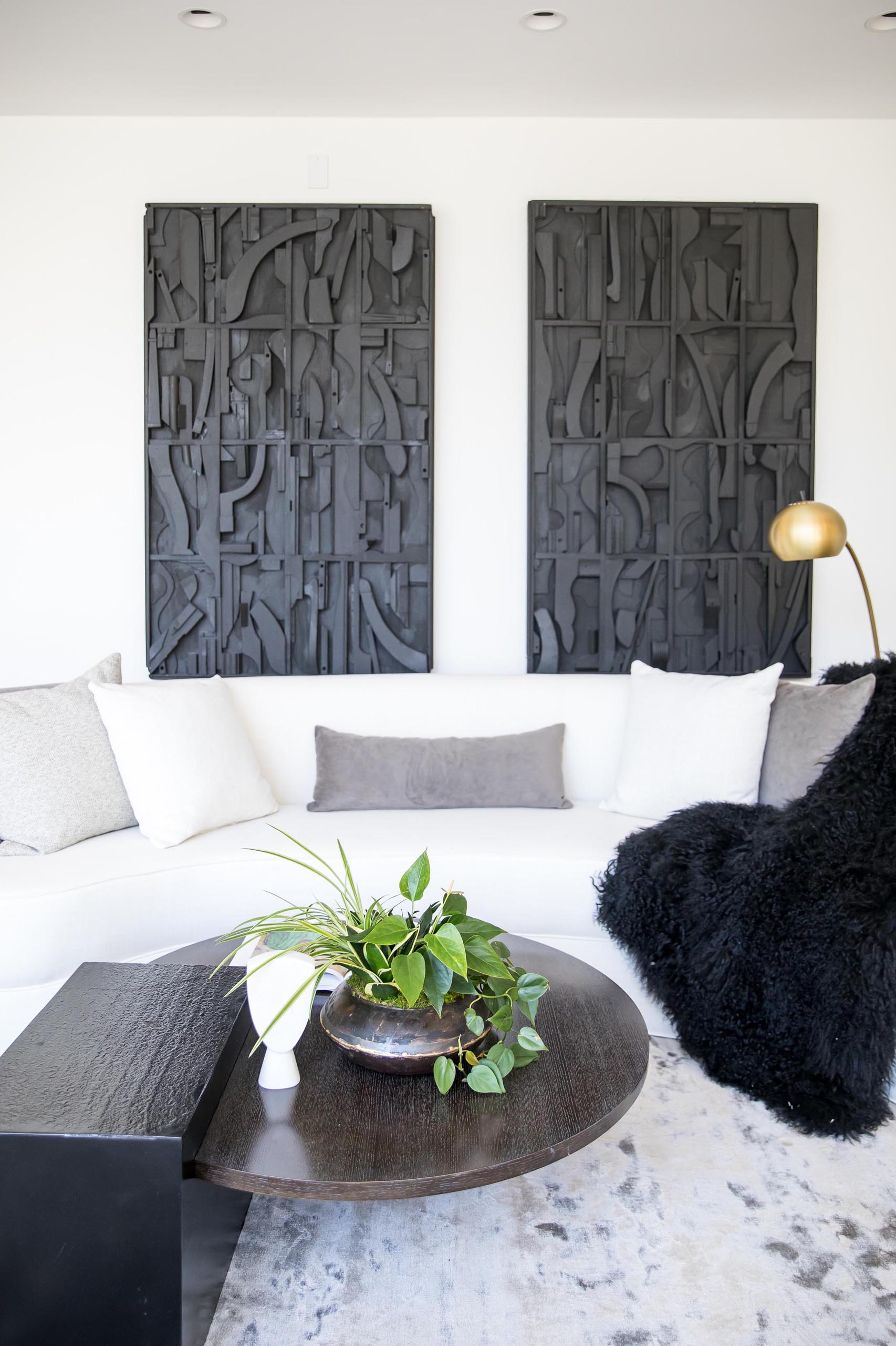 Современная гостиная с белым диваном и черными произведениями искусства.