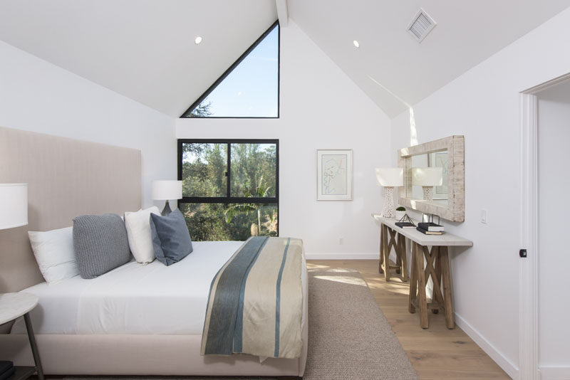 В этой современной спальне есть сводчатый потолок и треугольное окно, через которое ваш взгляд поднимается вверх на высоту комнаты.