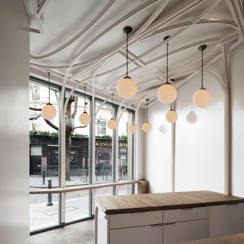 В этом кафе массивные импосты делятся пополам и выдавливаются из рам, образуя ленты, которые изгибаются и складываются по потолку в стиле, напоминающем орнаментальную штукатурку. # Архитектура # Дизайн интерьера # Дизайн кафе