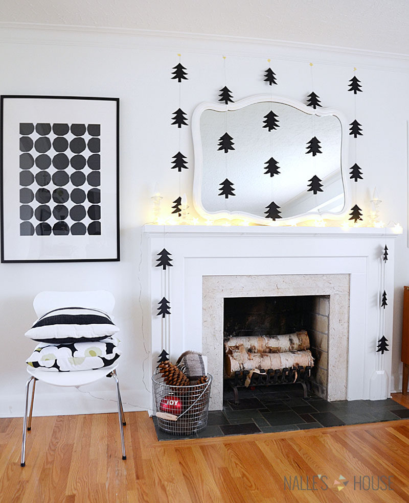 30 современных идей рождественского декора для вашего дома // Вырезы из черных бумажных елок, свисающие с потолка, обрамляют камин и делают комнату более уютной.