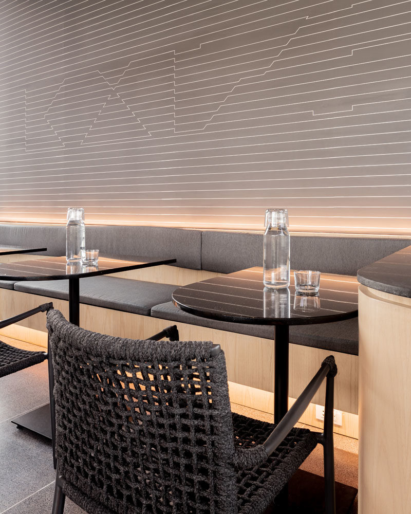 В этой современной кофейне есть скрытое освещение под столиками и за креслами, создающее мягкое свечение для черного, серого и деревянного интерьера. #ModernCoffeeShop #CafeDesign # Освещение