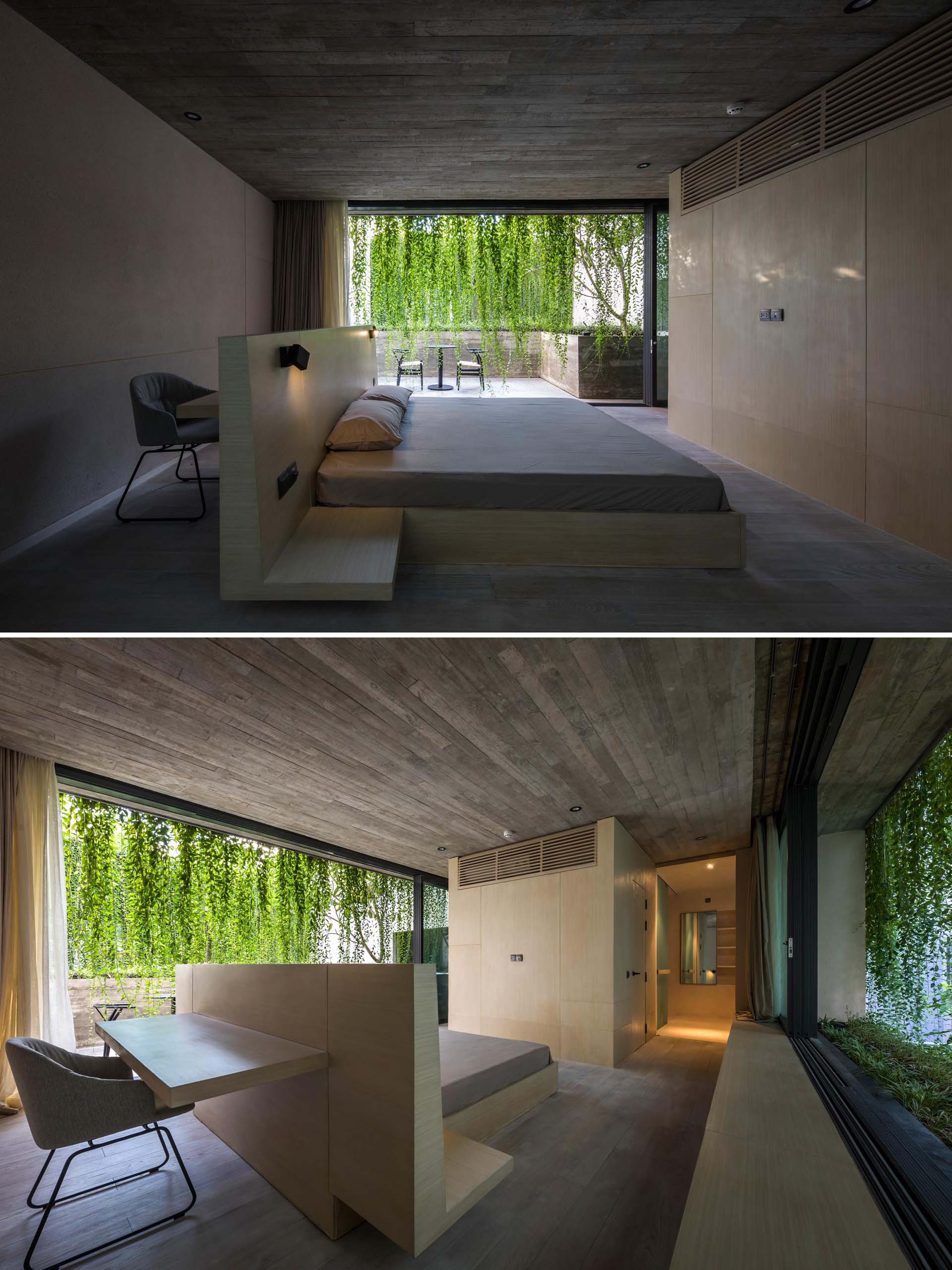 Спальня в стиле минимализма с бетонными стенами и каркасом кровати с письменным столом за изголовьем.