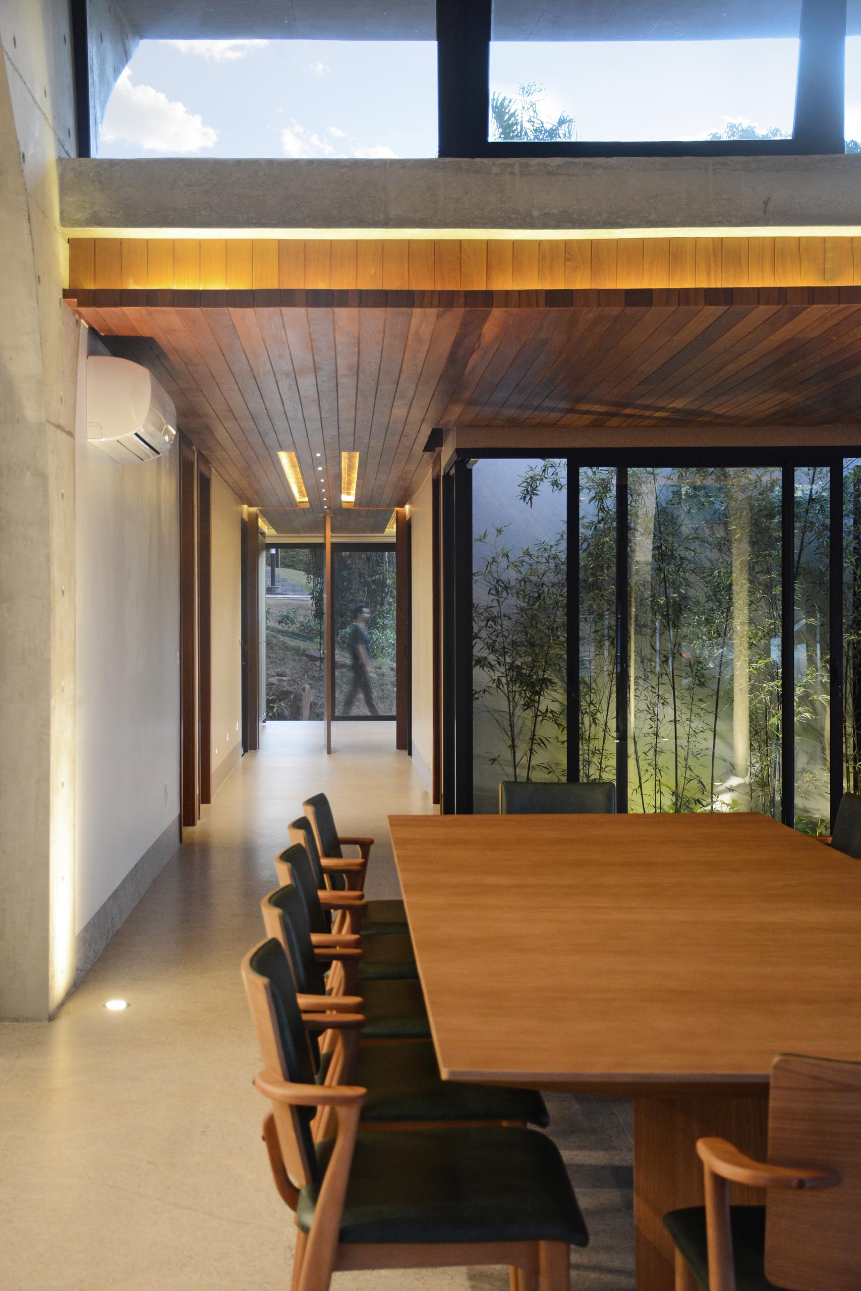 Поворотная входная дверь приветствует людей в доме, а деревянный потолок с подсветкой добавляет интерьеру ощущение тепла.