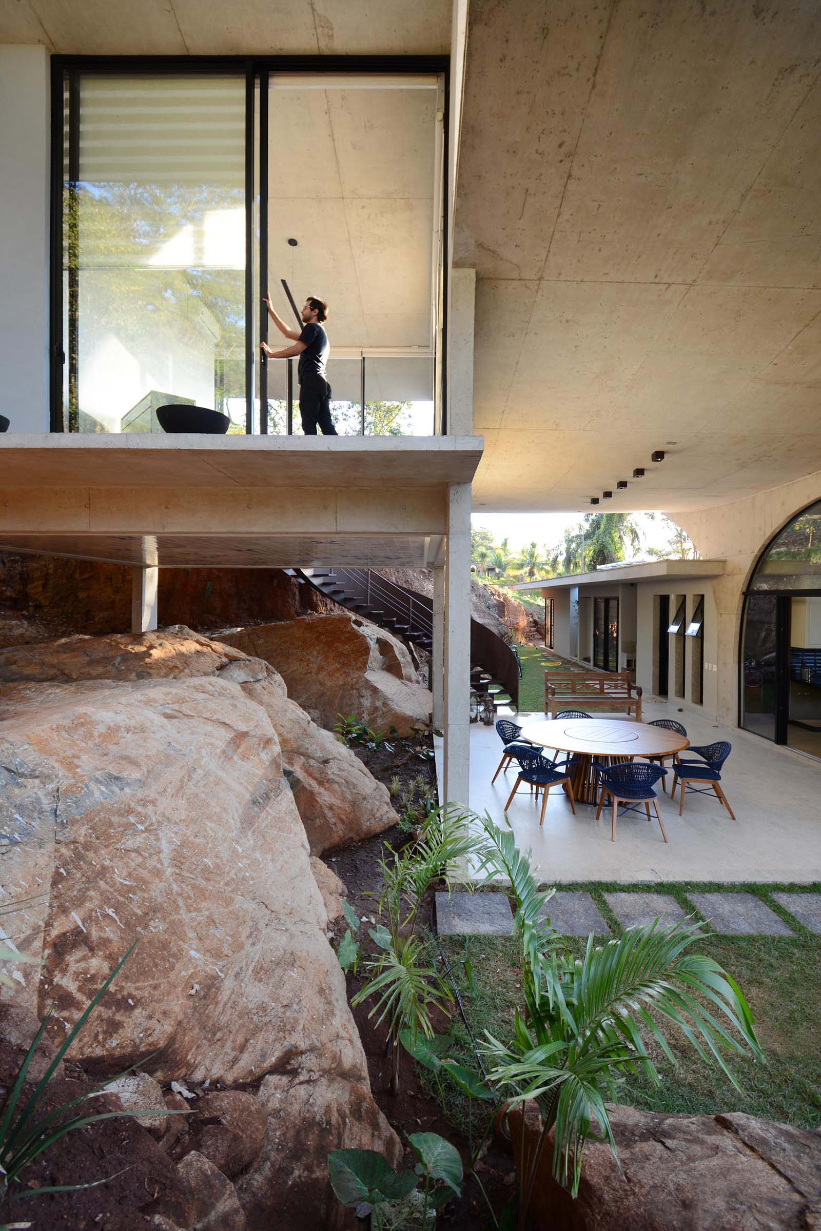 Современный бетонный дом с огромными раздвижными стеклянными дверями и крытым патио на открытом воздухе.