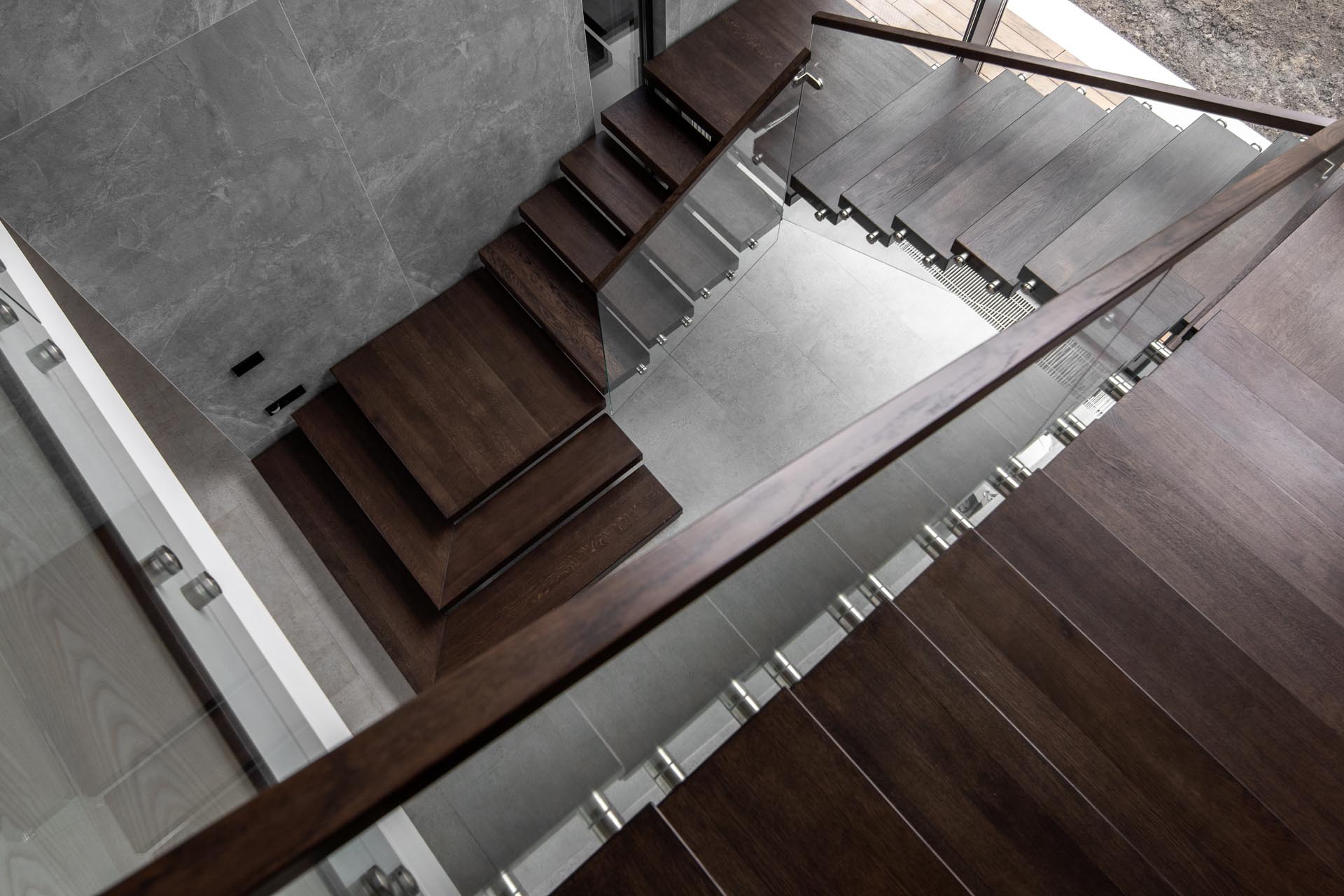 Современная деревянная лестница со стеклянными перилами.
