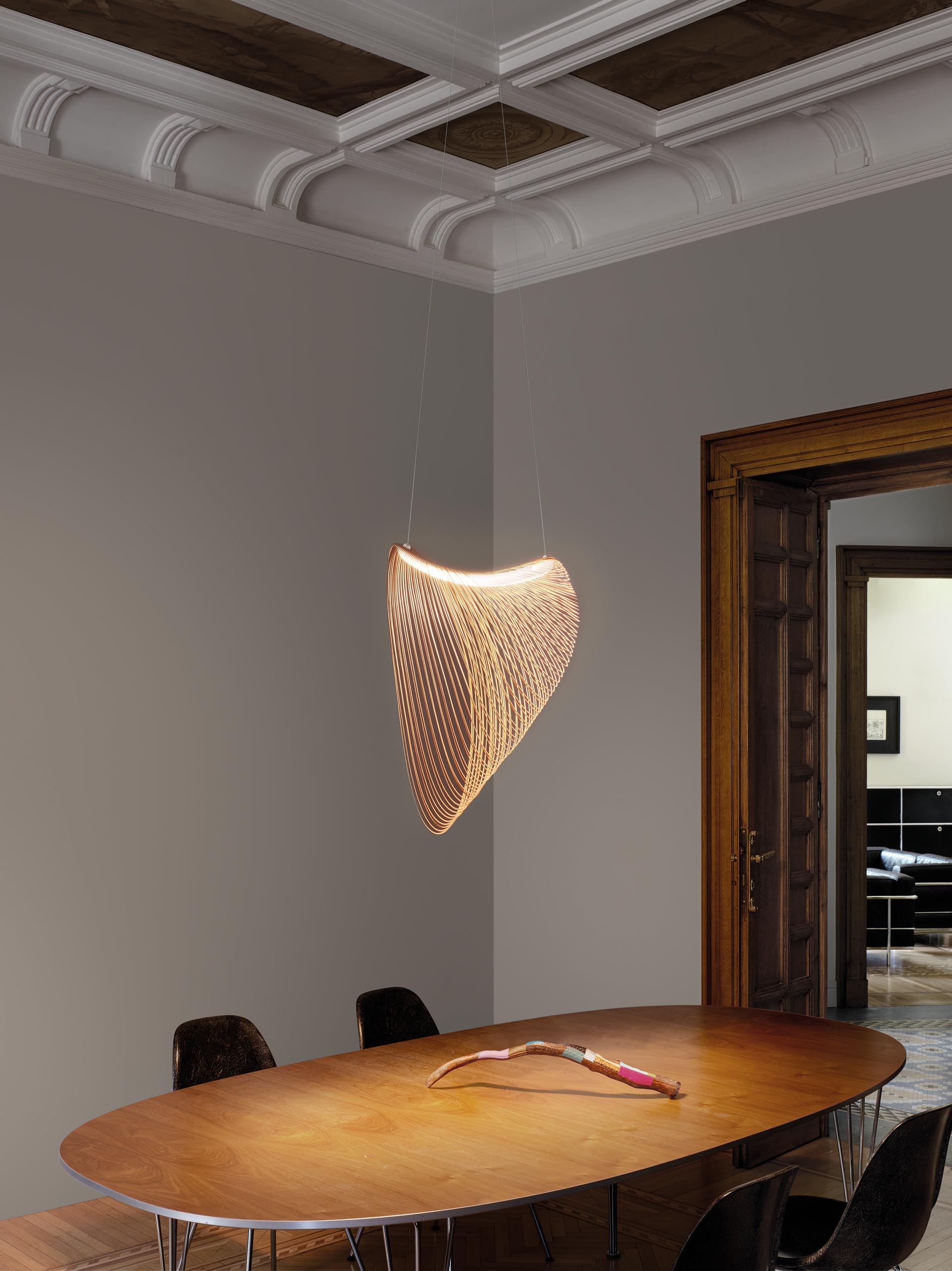 Изящный подвесной светильник из дерева, вырезанного лазером, со светодиодами висит над обеденным столом.