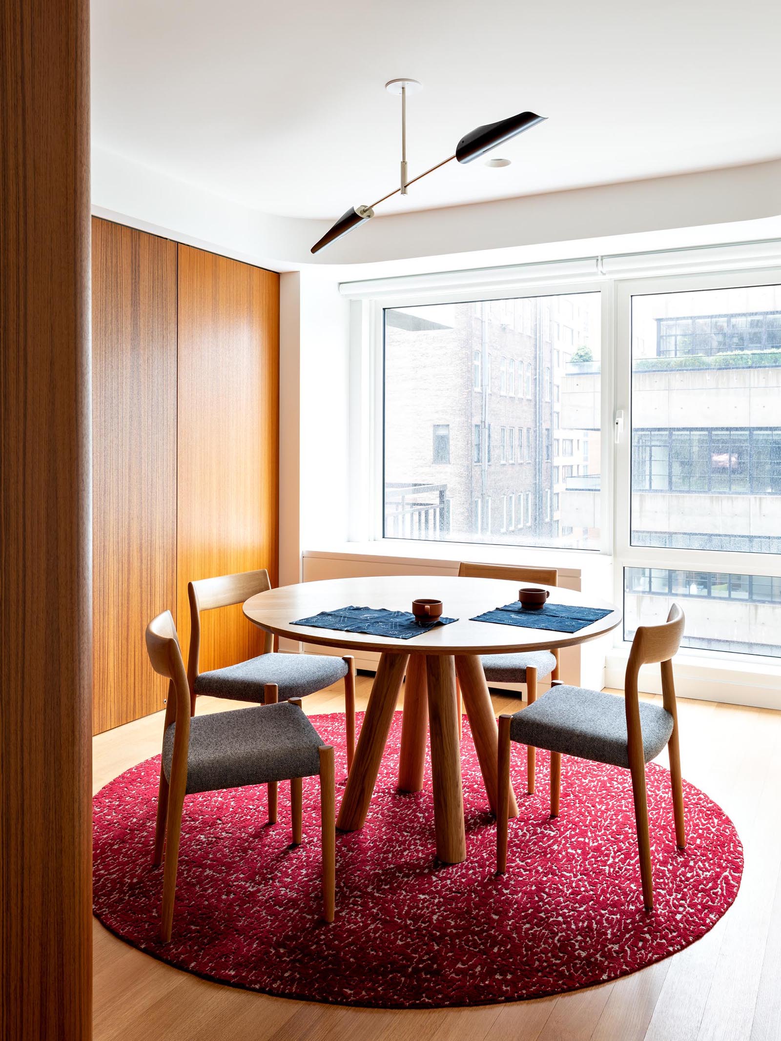 Современная столовая с красочным бордово-розовым ковром и деревянной мебелью.