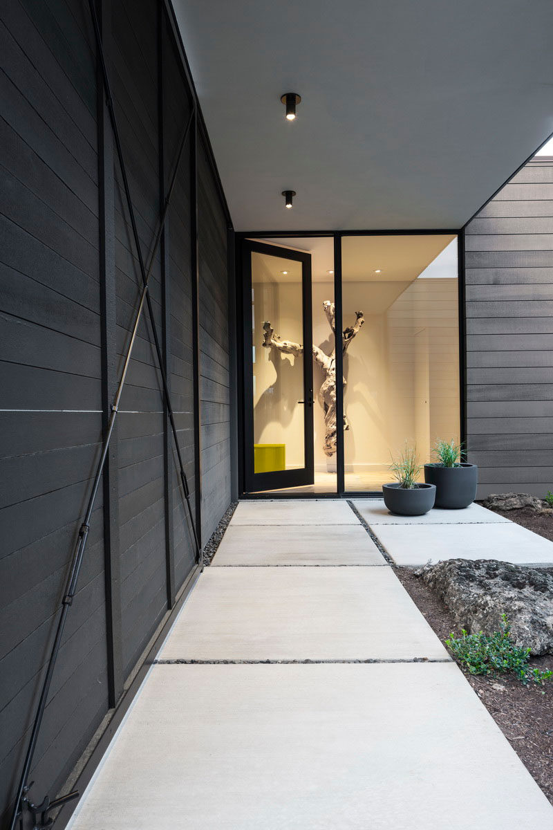 Во внутреннем дворе этого современного дома раздвижные ширмы и распашные ворота могут быть уютными и приватными или широко открытыми и гостеприимными. #ModernHouse #GlassDoor #ConcretePath