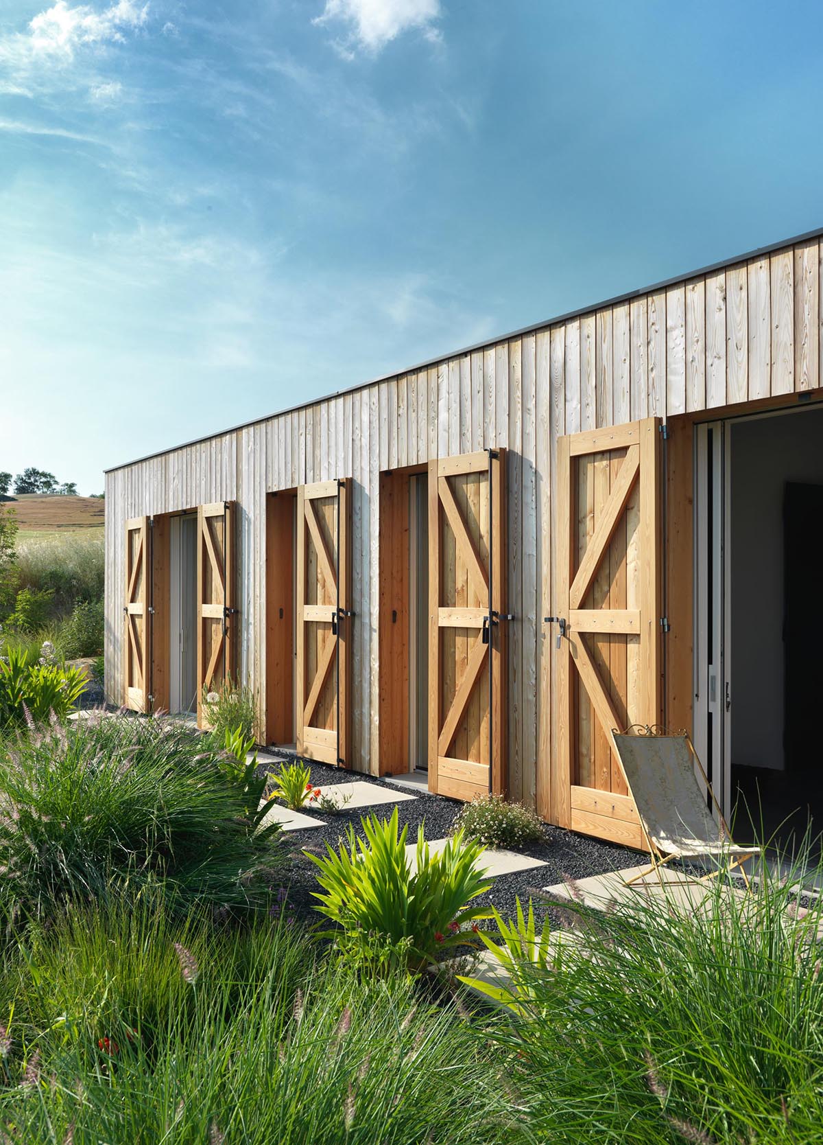 Современный фермерский дом с деревянными ставнями для защиты окон и дверей.