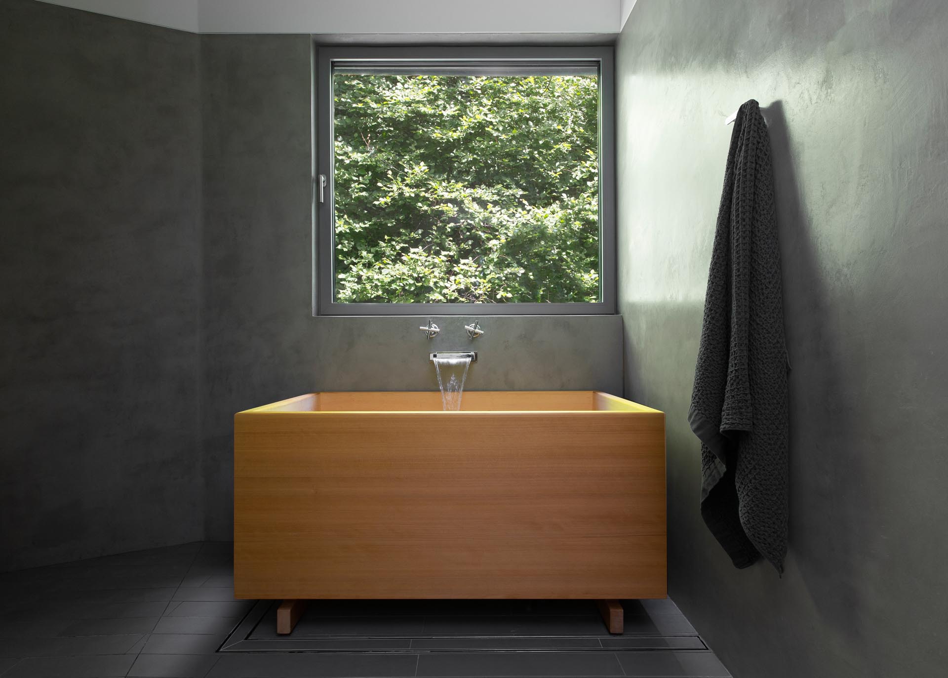 Современная ванная комната с темно-серыми стенами и деревянной японской ванной.