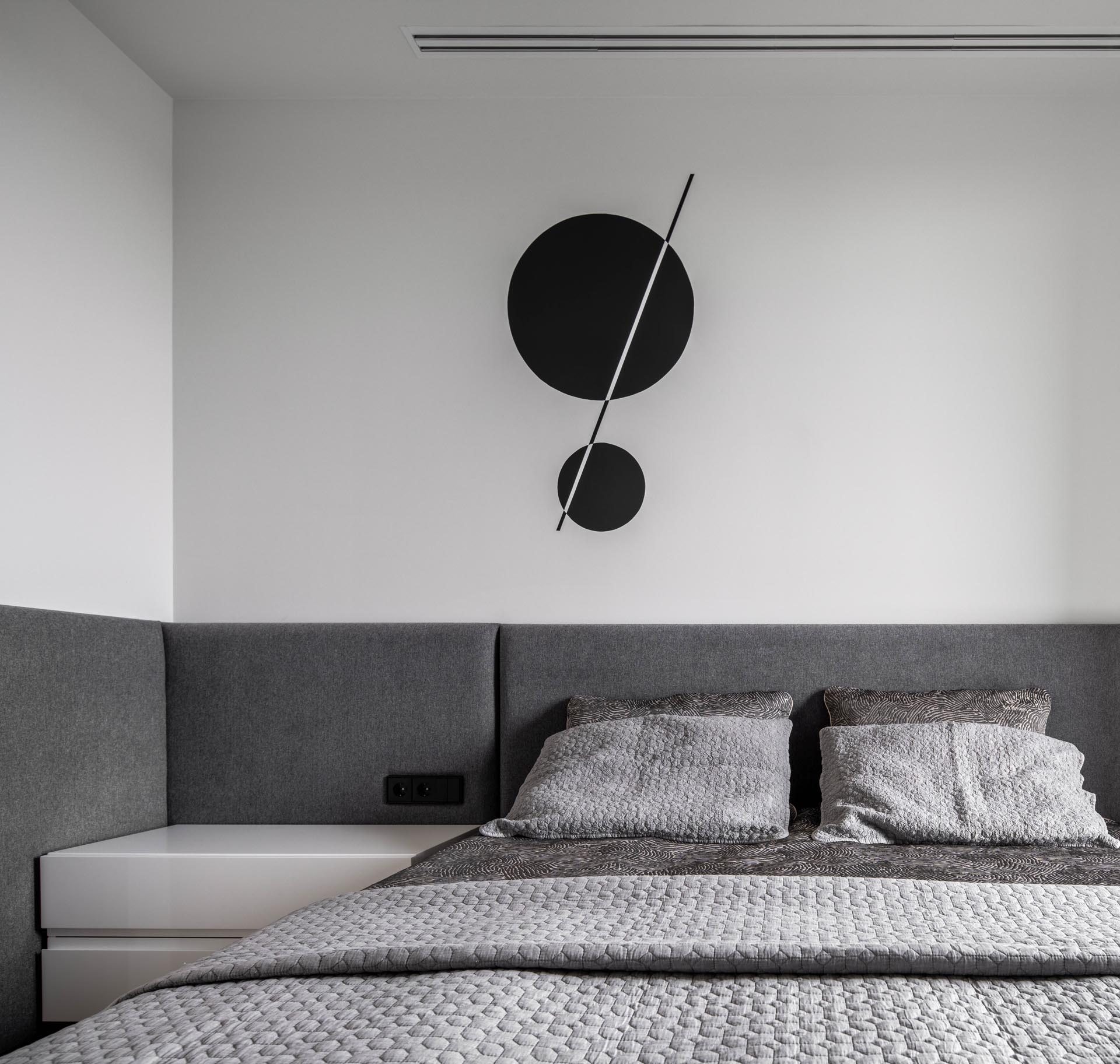 Современная спальня в стиле отеля с серым изголовьем по периметру.