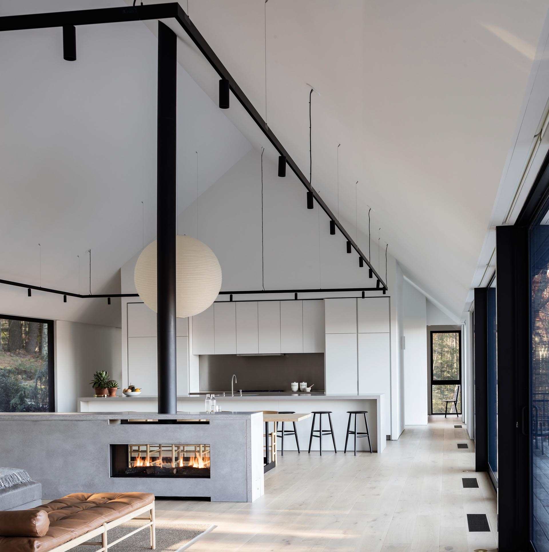 Интерьер современного дома с прозрачным камином, минималистской белой кухней и черными акцентами.