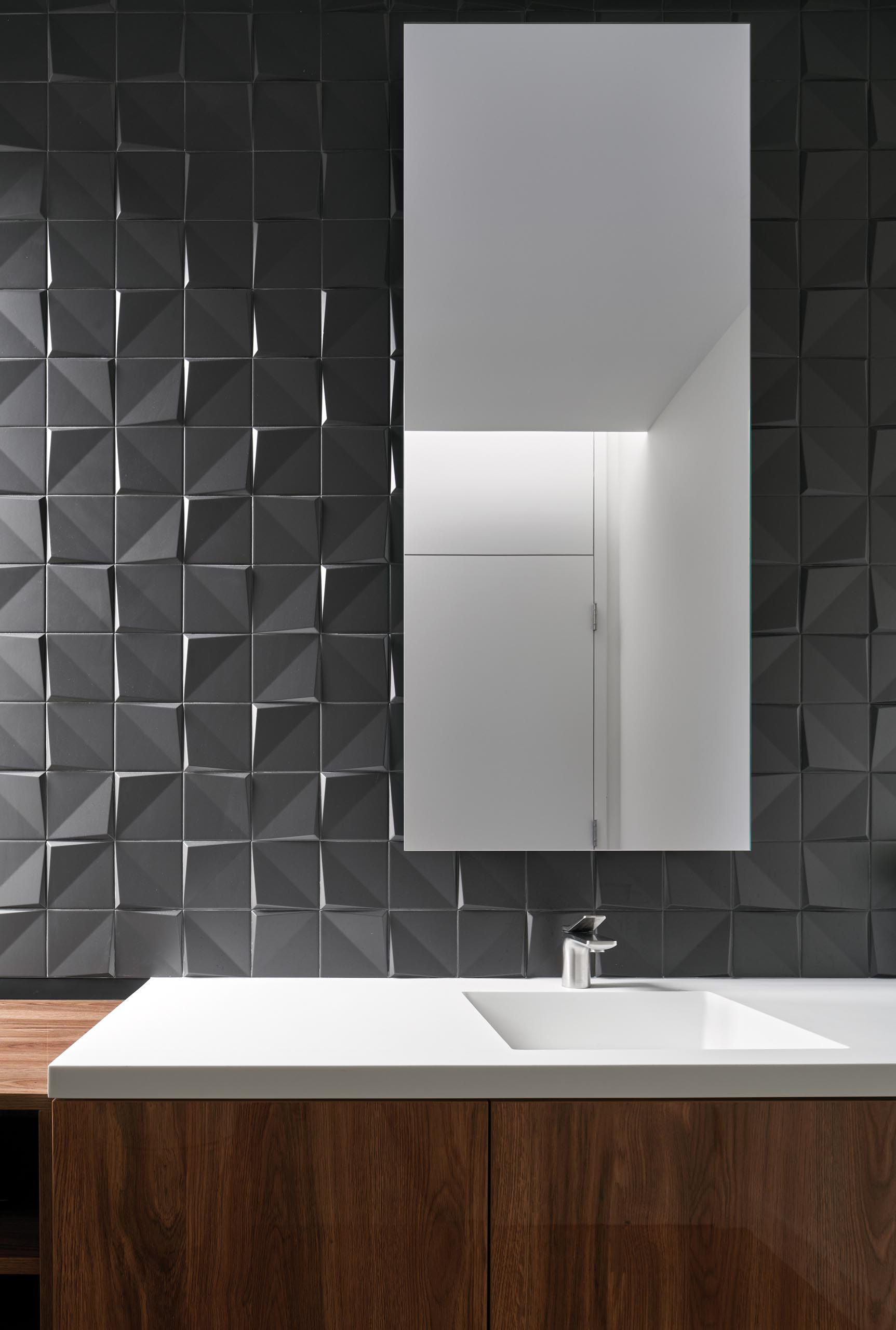 Современная серая и деревянная ванная комната с трехмерной плиткой, придающей текстуру стене.
