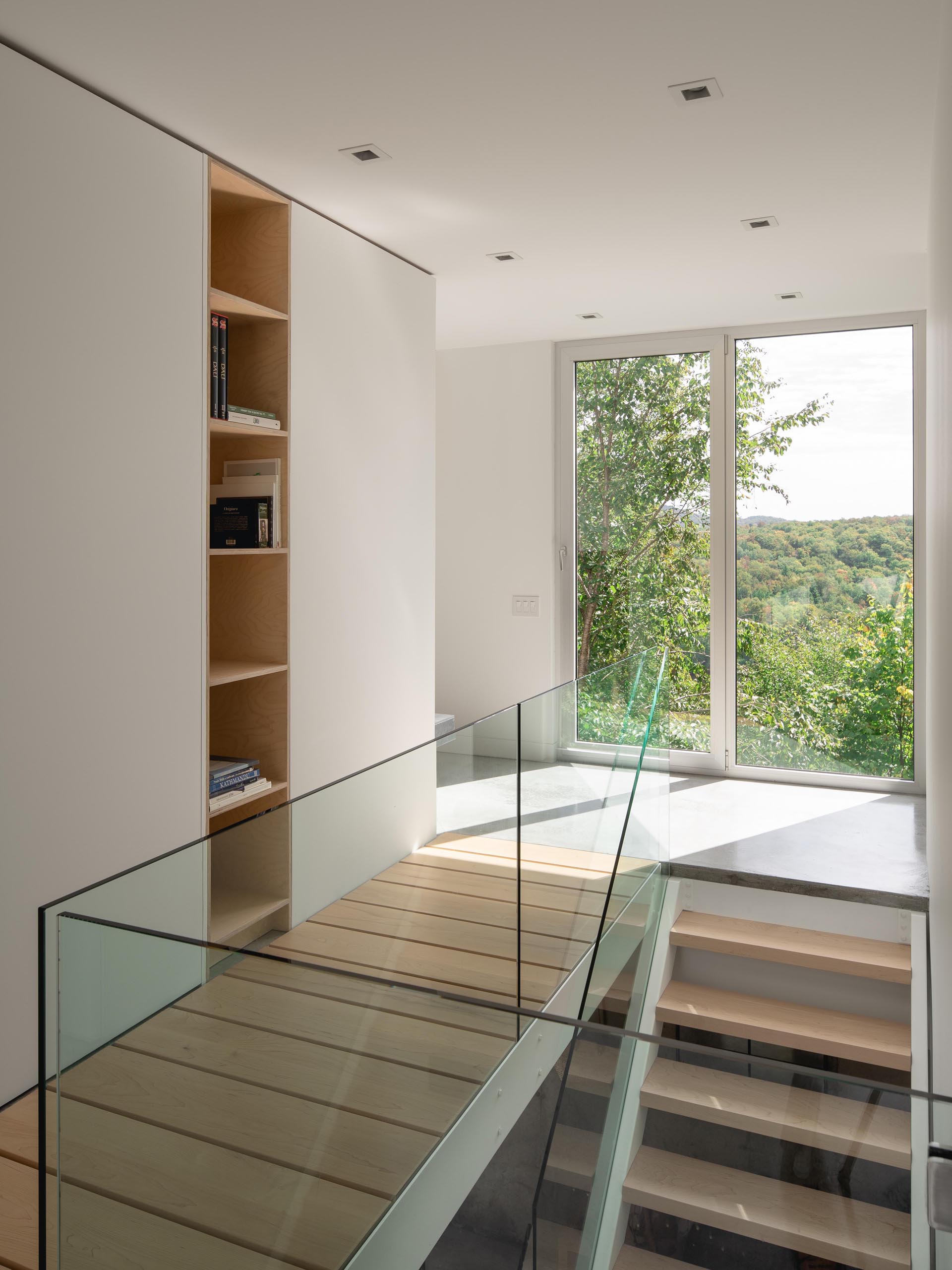 Современный домашний интерьер с деревянной лестницей и стеклянными перилами.