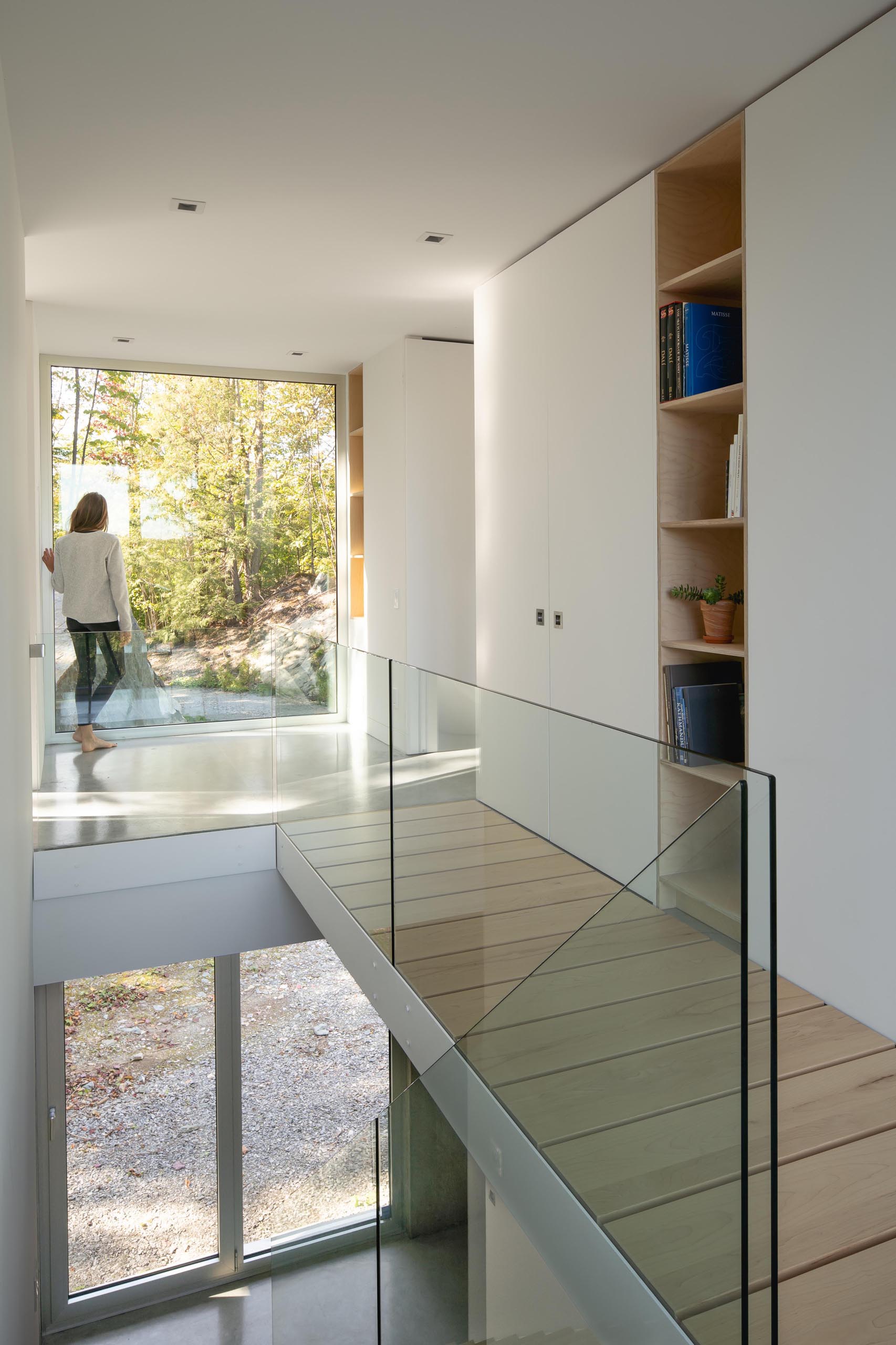 Современный домашний интерьер с деревянной лестницей и стеклянными перилами.