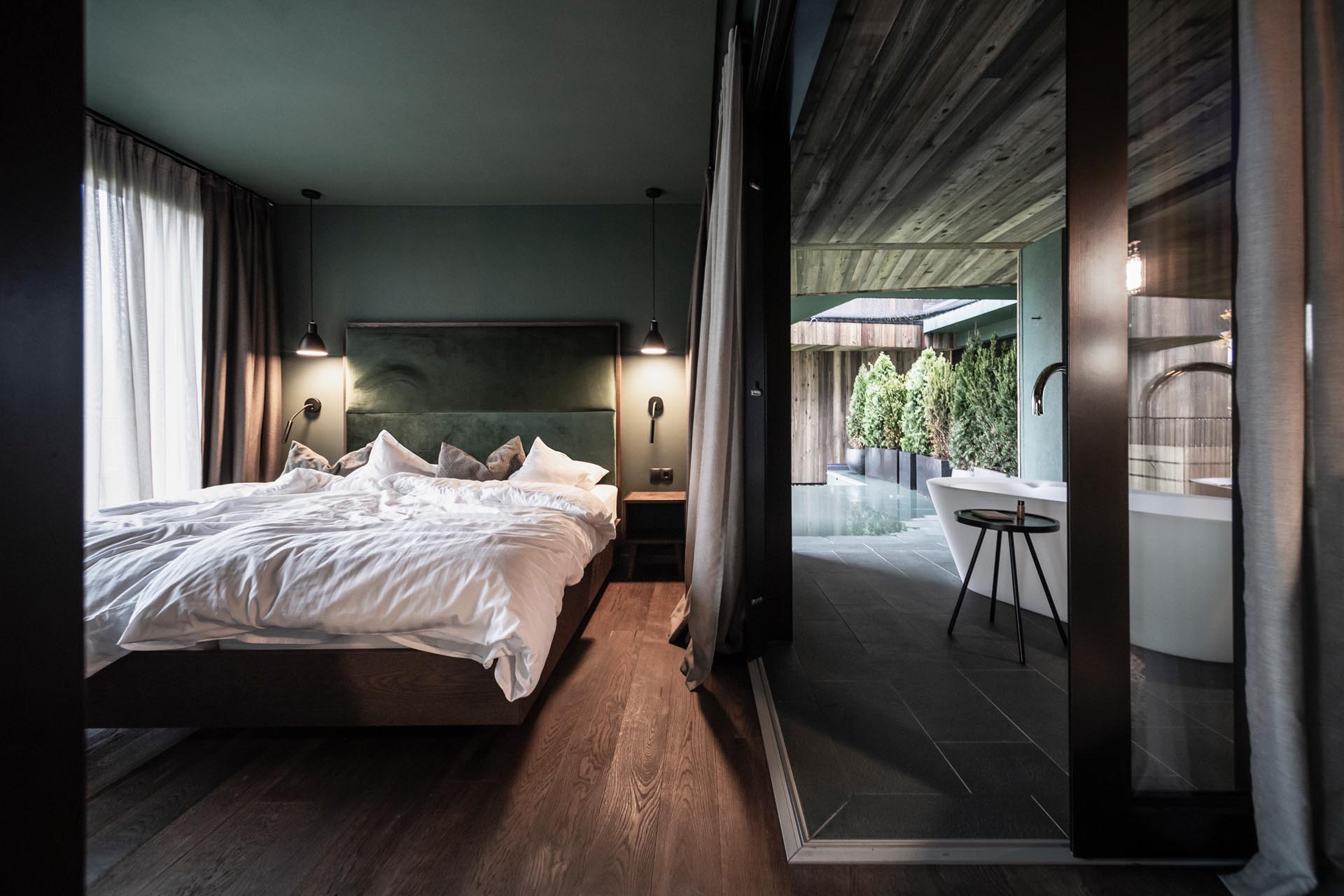 Современный гостиничный номер со стеклянной спальней и ваннами на открытом воздухе.