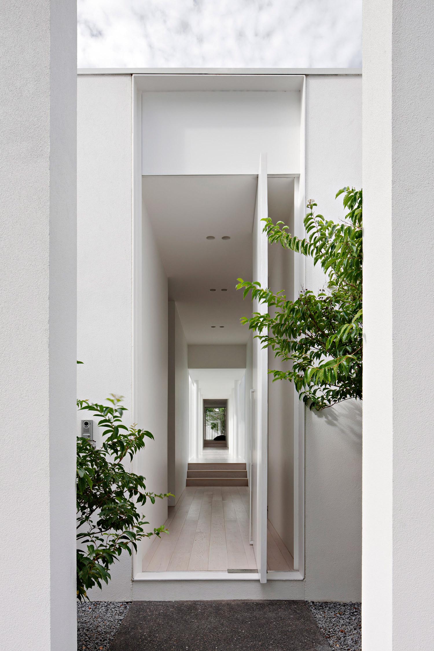 Современный дом белого цвета с белой поворотной входной дверью.