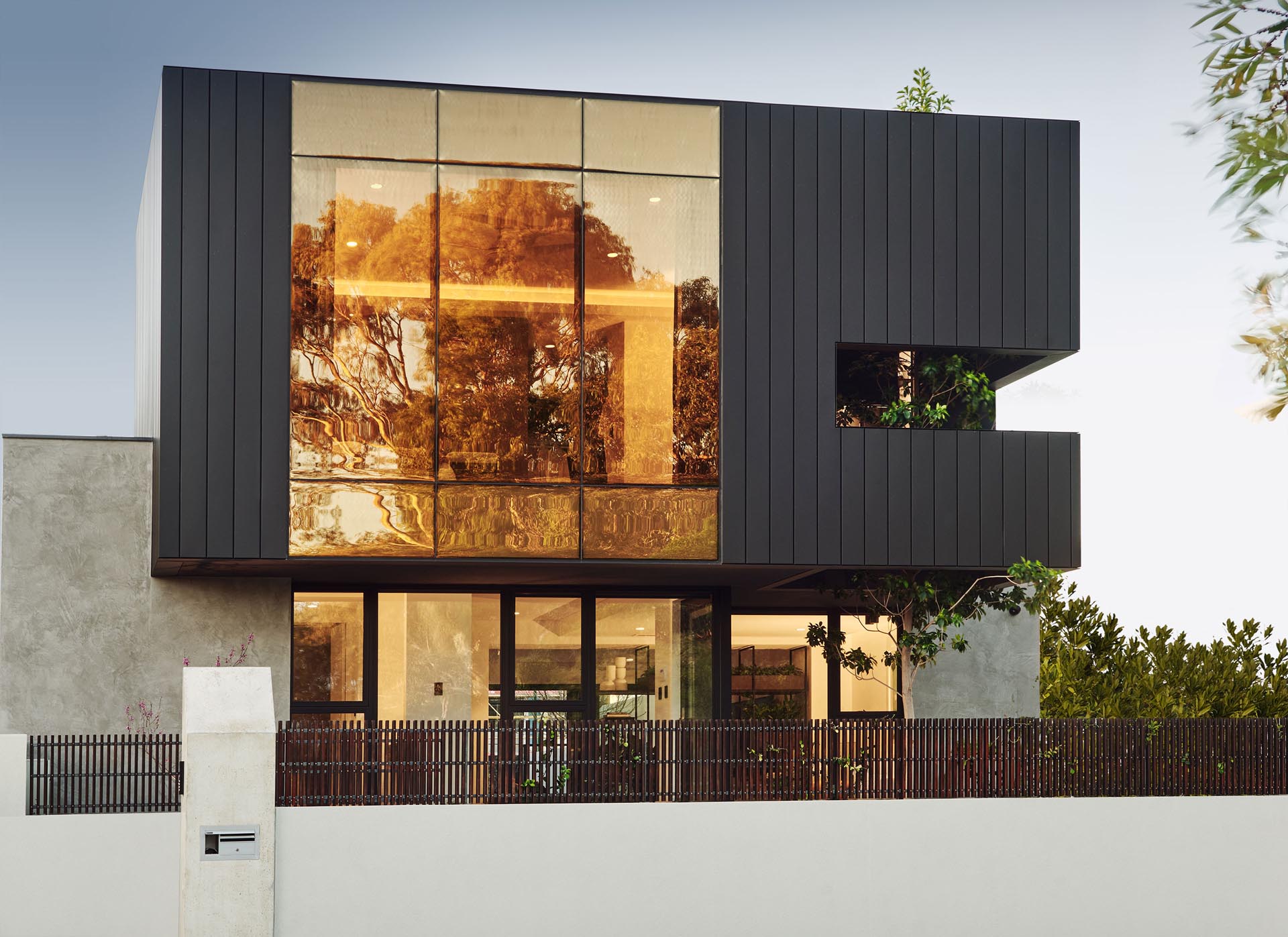 Фасад этого современного дома отличается супербронзовой стеной с двойным остеклением, которая сочетается с матовым сайдингом.