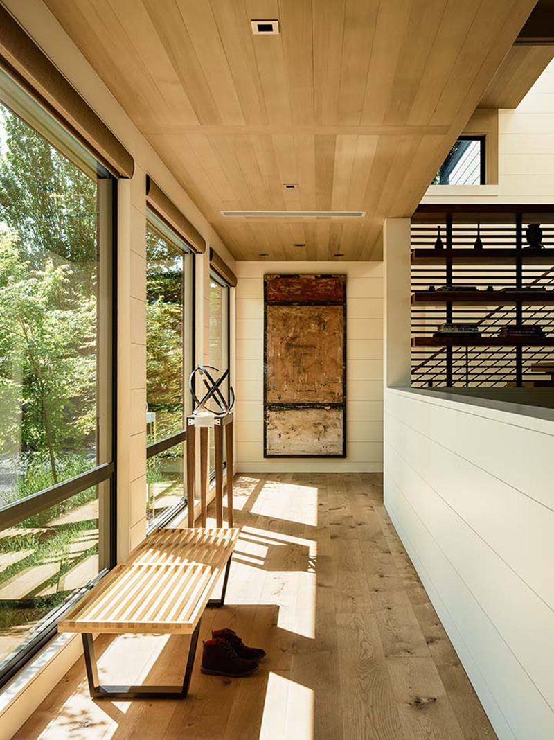 Современный коридор с деревянным полом, деревянным потолком и высокими окнами.