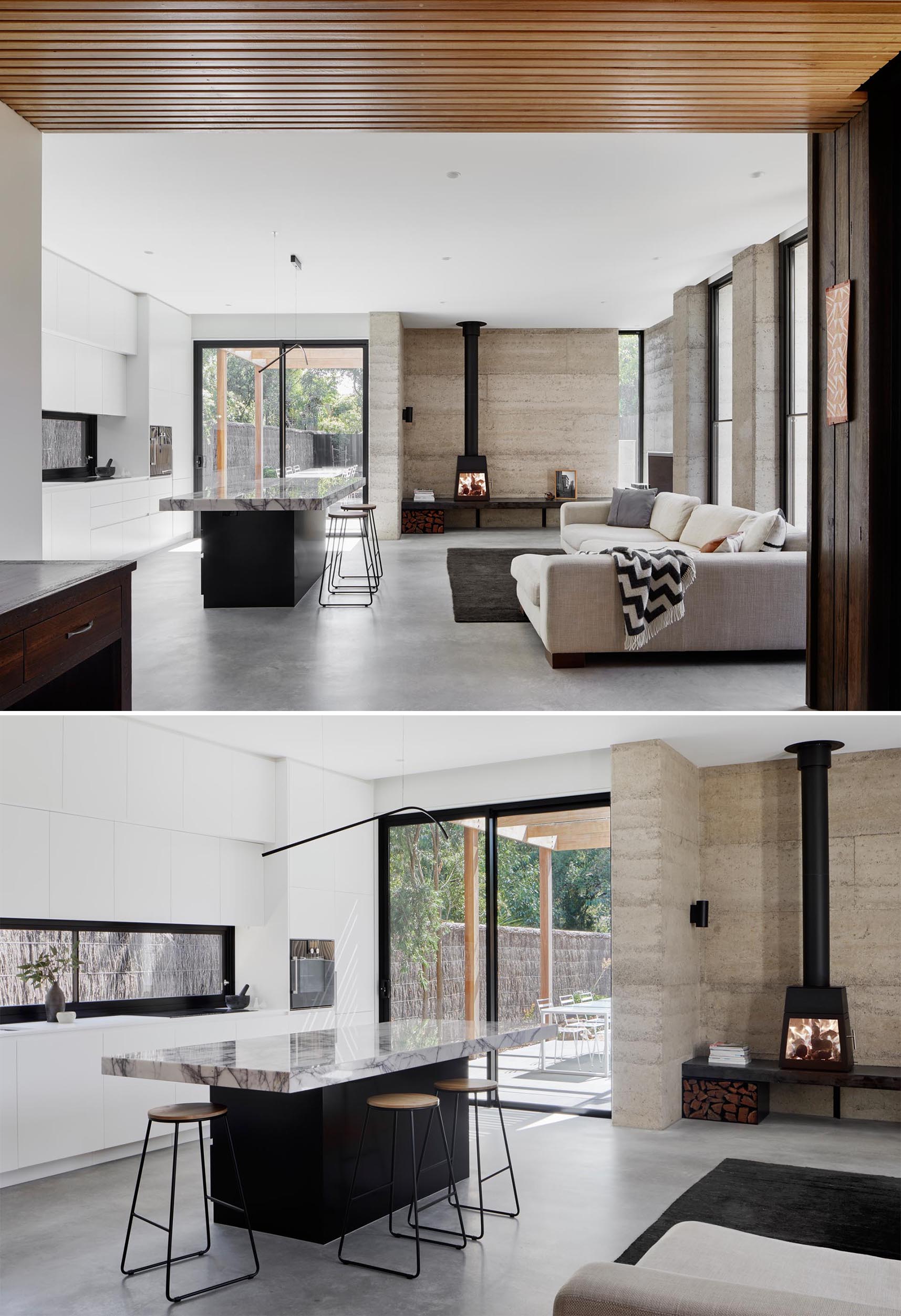 В этой современной гостиной и кухне открытой планировки есть земляная стена за камином и бетонный пол.