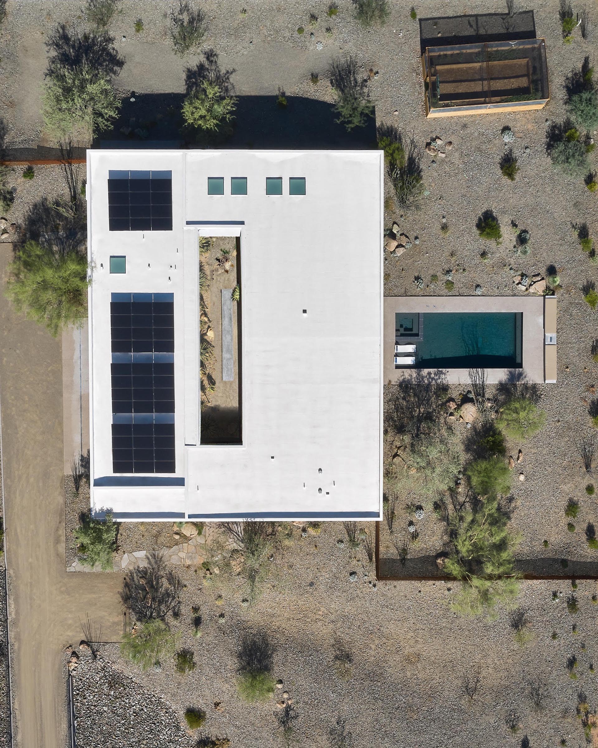 Современный дом в пустыне с центральным двором, бассейном и солнечной батареей на крыше.