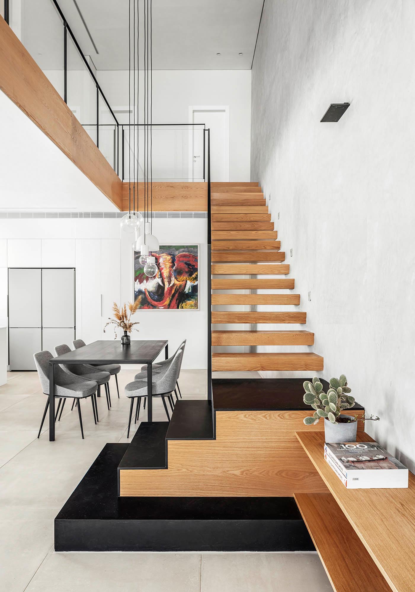 Плавающая дубовая лестница соединяет различные уровни этого современного дома, включает в себя черные железные лестницы внизу и переходы, которые превращаются в буфет для телевизора в гостиной.