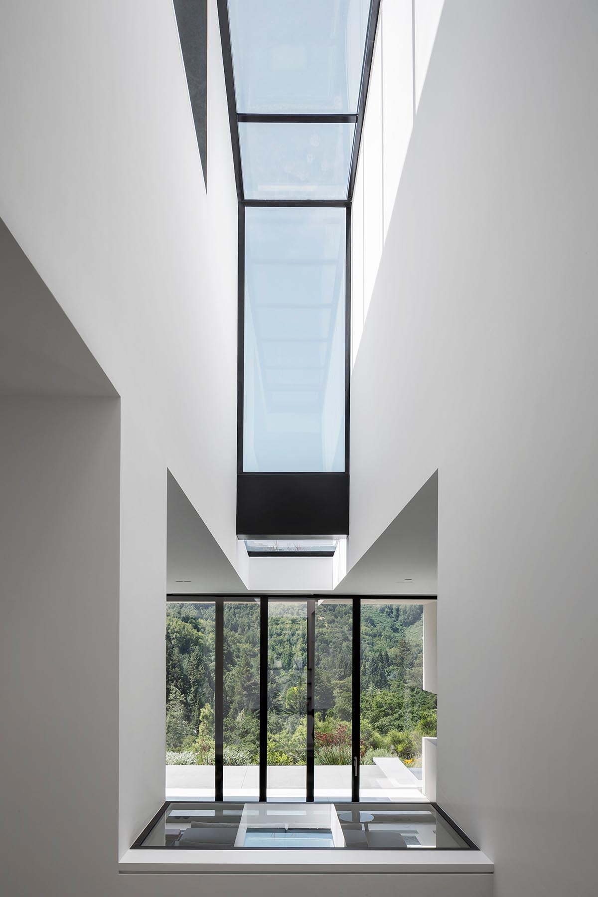 В этом современном доме есть окно, которое пересекает внутреннее пространство двойной высоты.