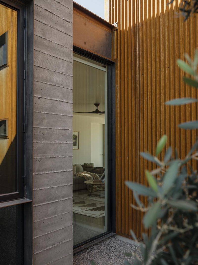 Современный дом с бетонными стенами из досок, стальными балками и гофрированным металлическим сайдингом.
