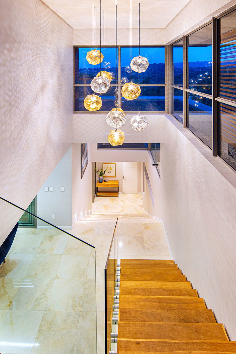 Идеи для лестниц - в этом современном доме есть деревянные лестницы со стеклянными поручнями, которые соединяют разные этажи дома, а также коллекция металлических подвесных светильников, которые наполняют пространство светом. #StairIdeas #LightingIdeas # ModernStairs