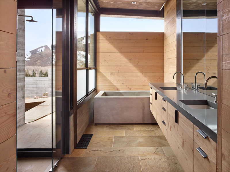 В этой современной промышленной ванной комнате деревянная и каменная плитка сочетаются с бетонной ванной. В душе есть окно от пола до потолка, так что вы можете наслаждаться видом на горы во время отдыха.
