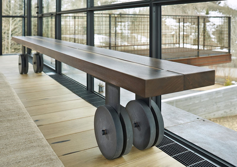 Деревянная скамейка продолжает индустриальную тему всего дома со стальными колесами, прикрепленными к ножкам.